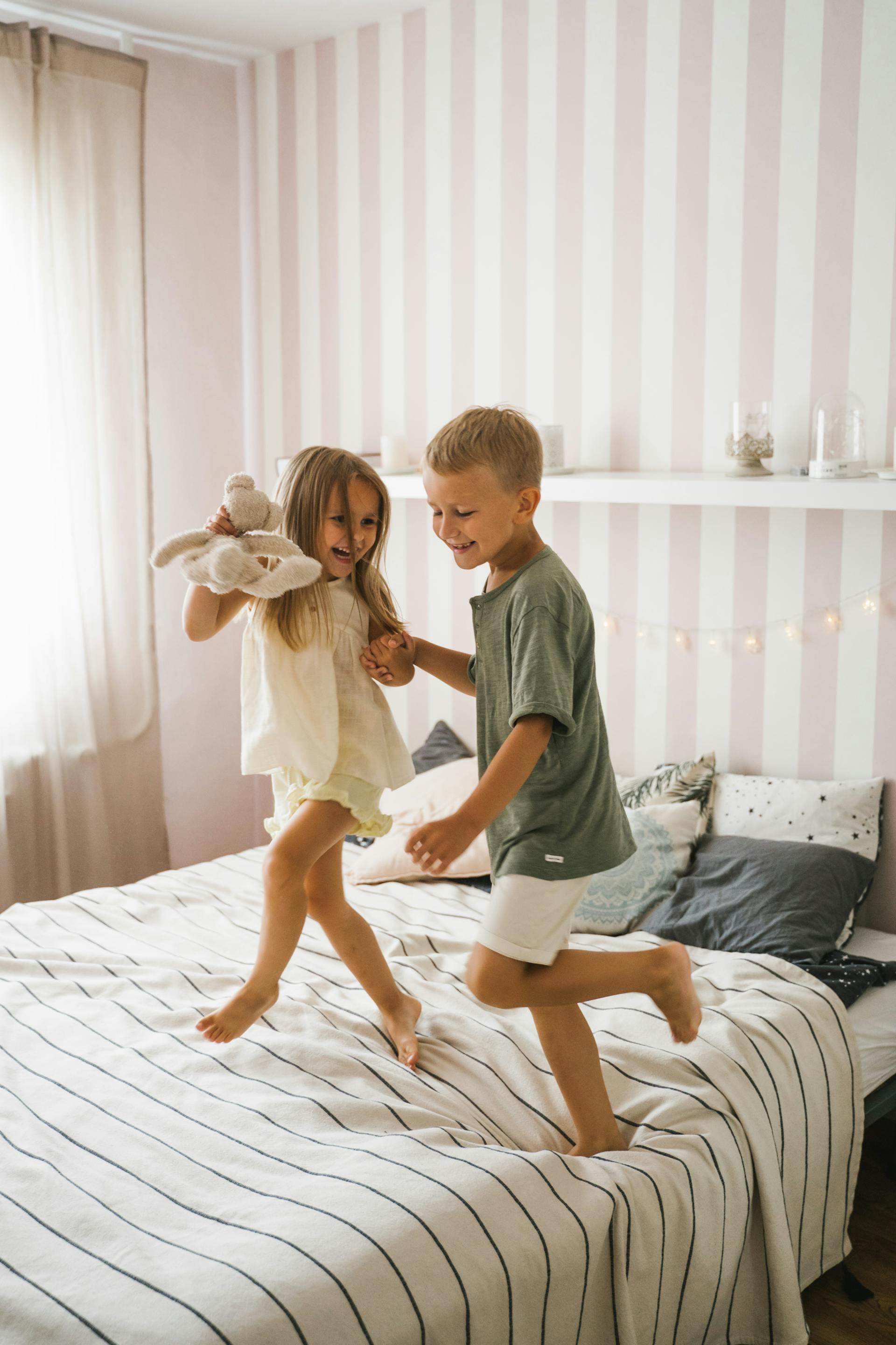 Niños felices bailando en la cama | Fuente: Pexels