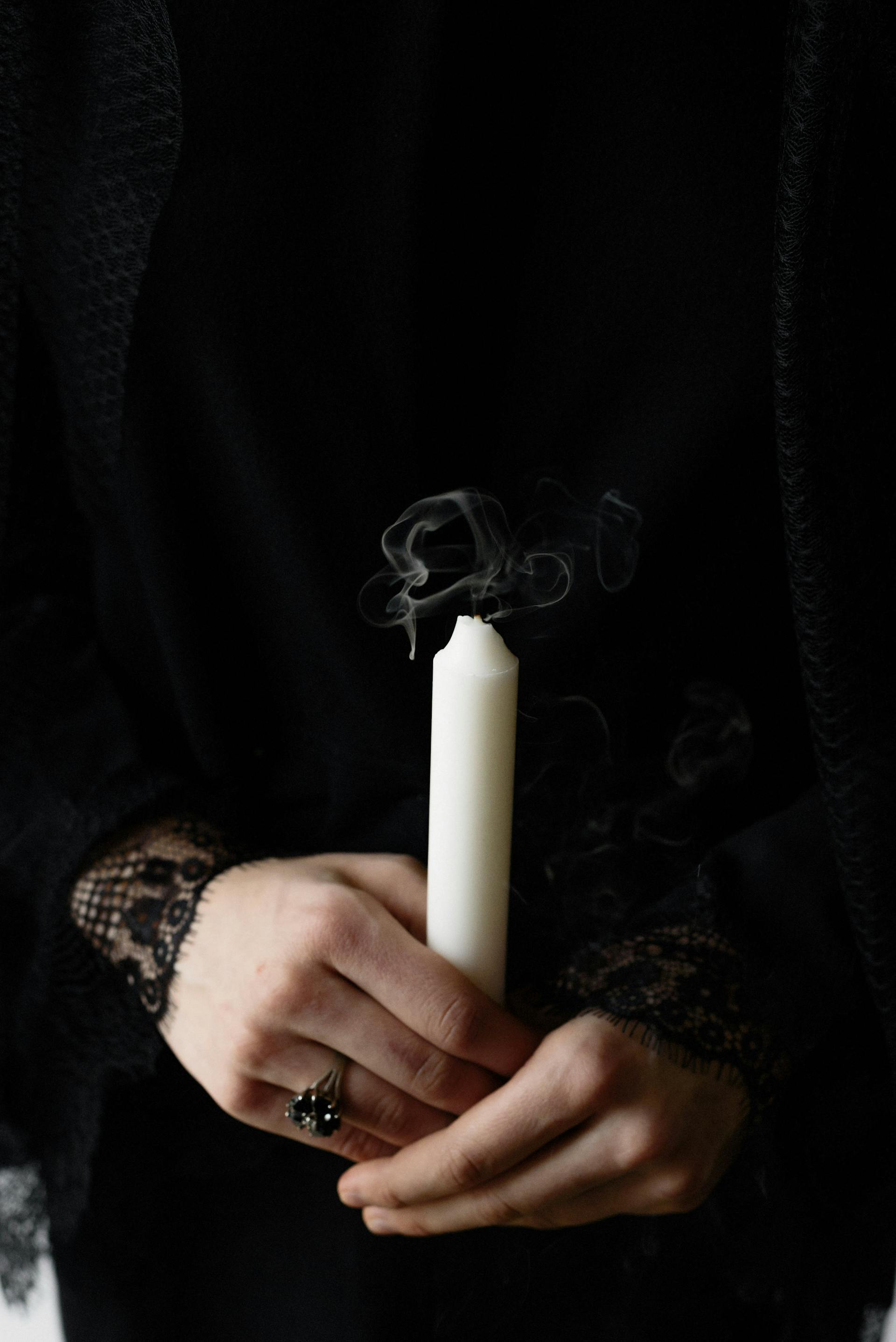 Primer plano de una mujer sosteniendo una vela blanca | Fuente: Pexels