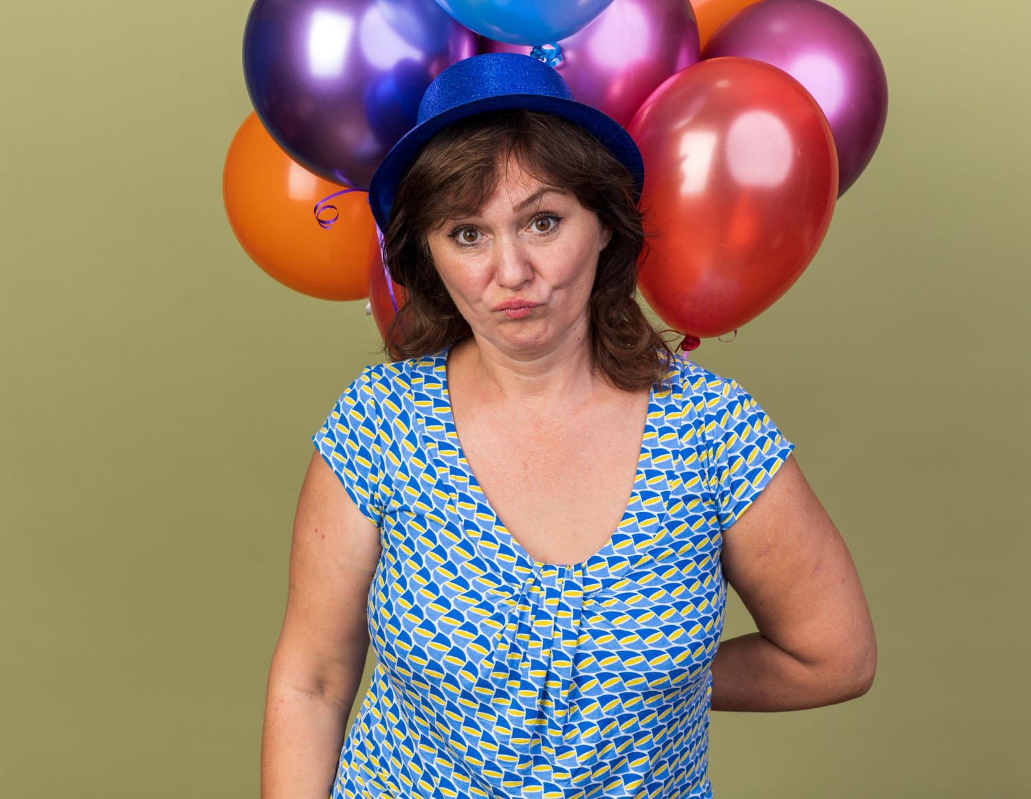 Una mujer atónita sosteniendo globos de colores | Fuente: Freepik