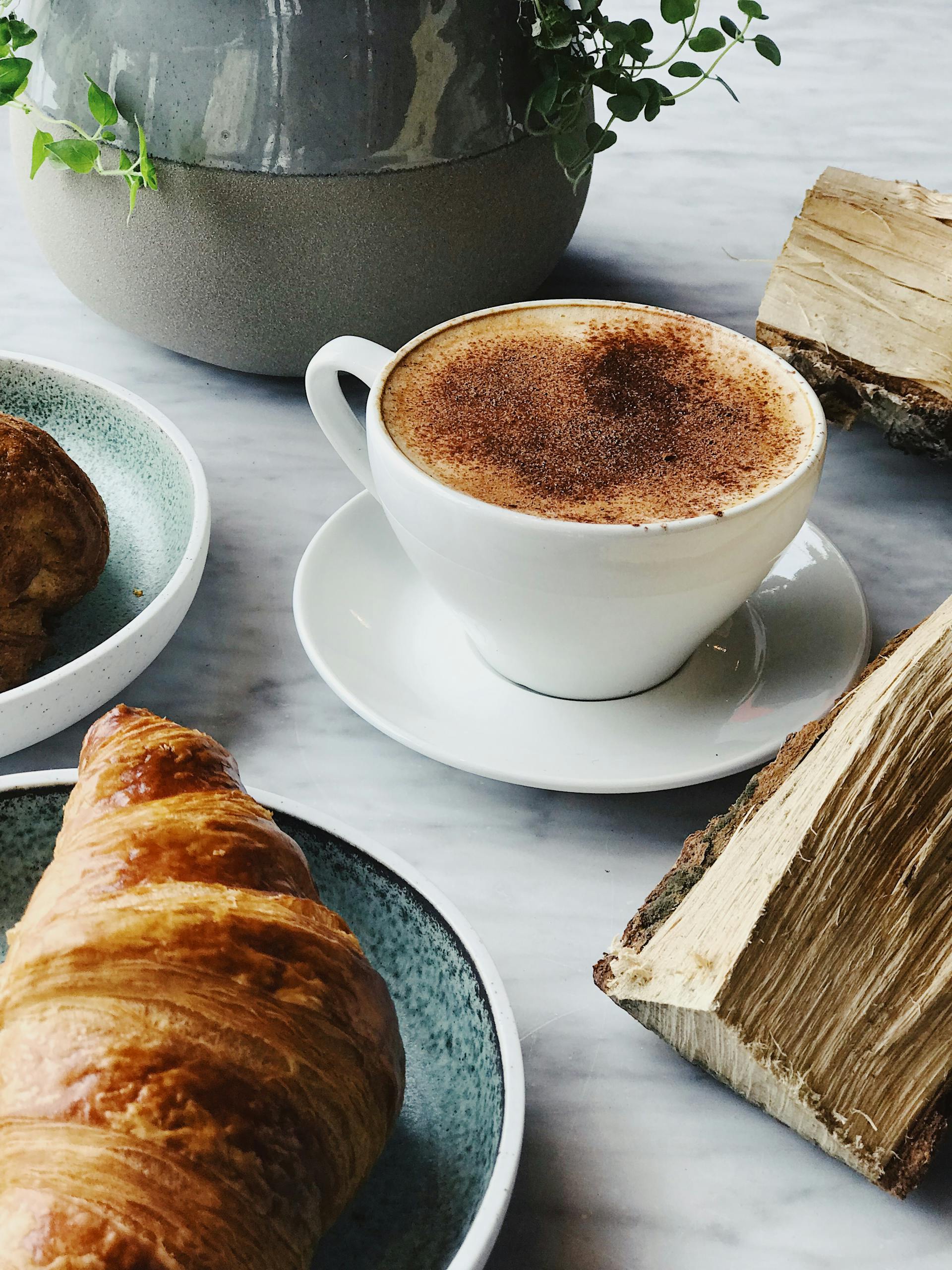 Una taza de café y un cruasán sobre una mesa | Fuente: Pexels