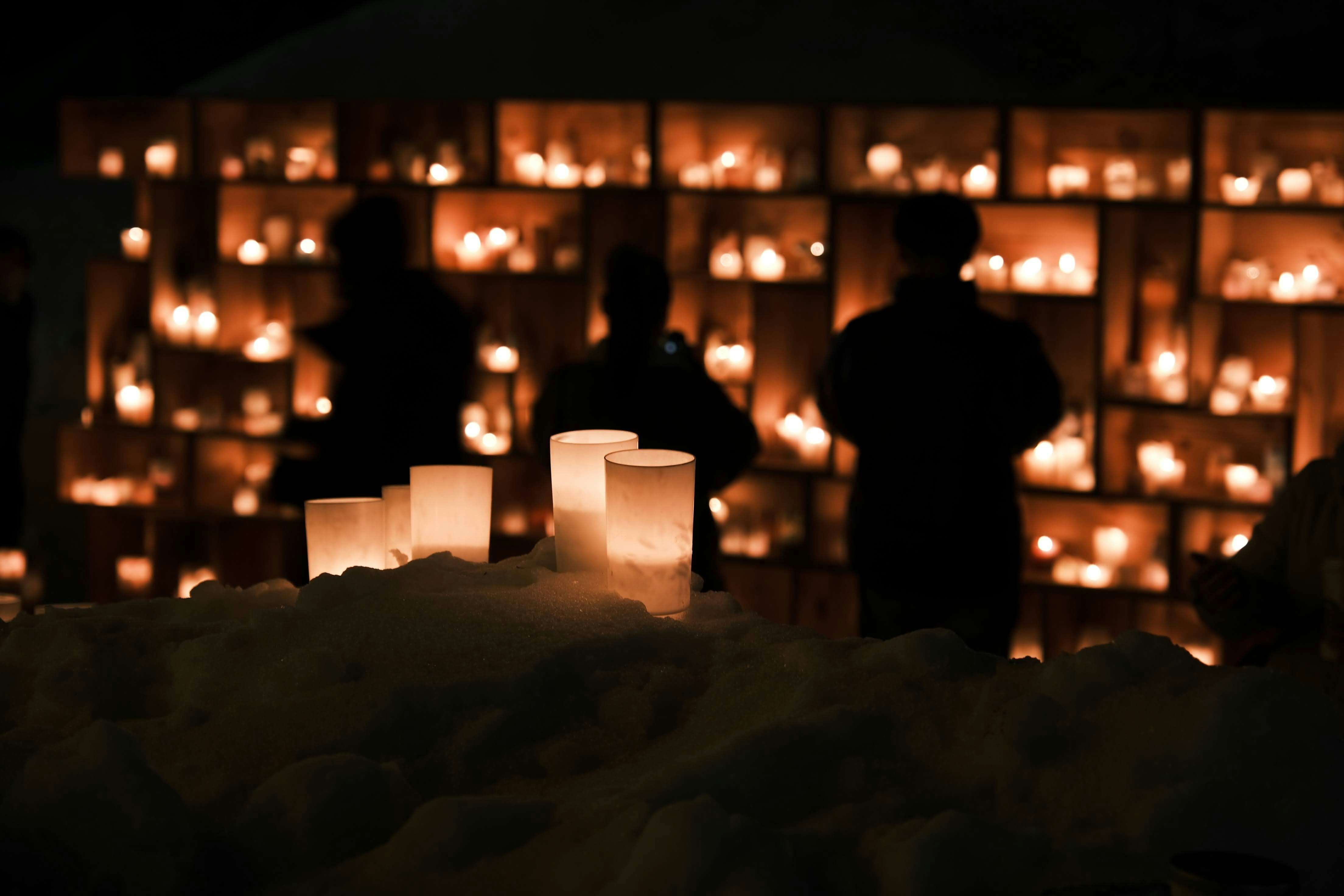 Gente delante de un muro de velas | Fuente: Pexels