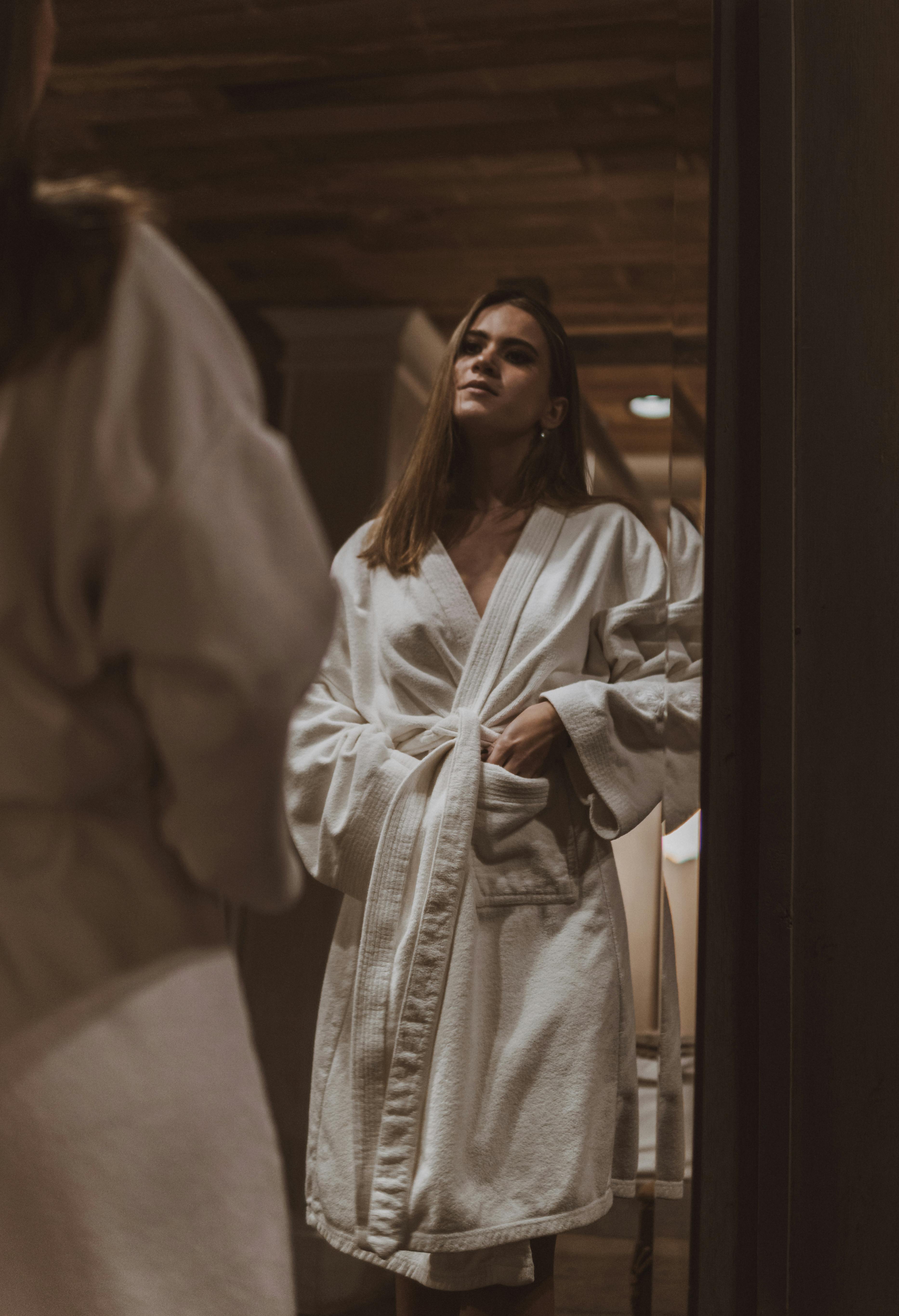 Una mujer en albornoz mirándose al espejo | Fuente: Pexels