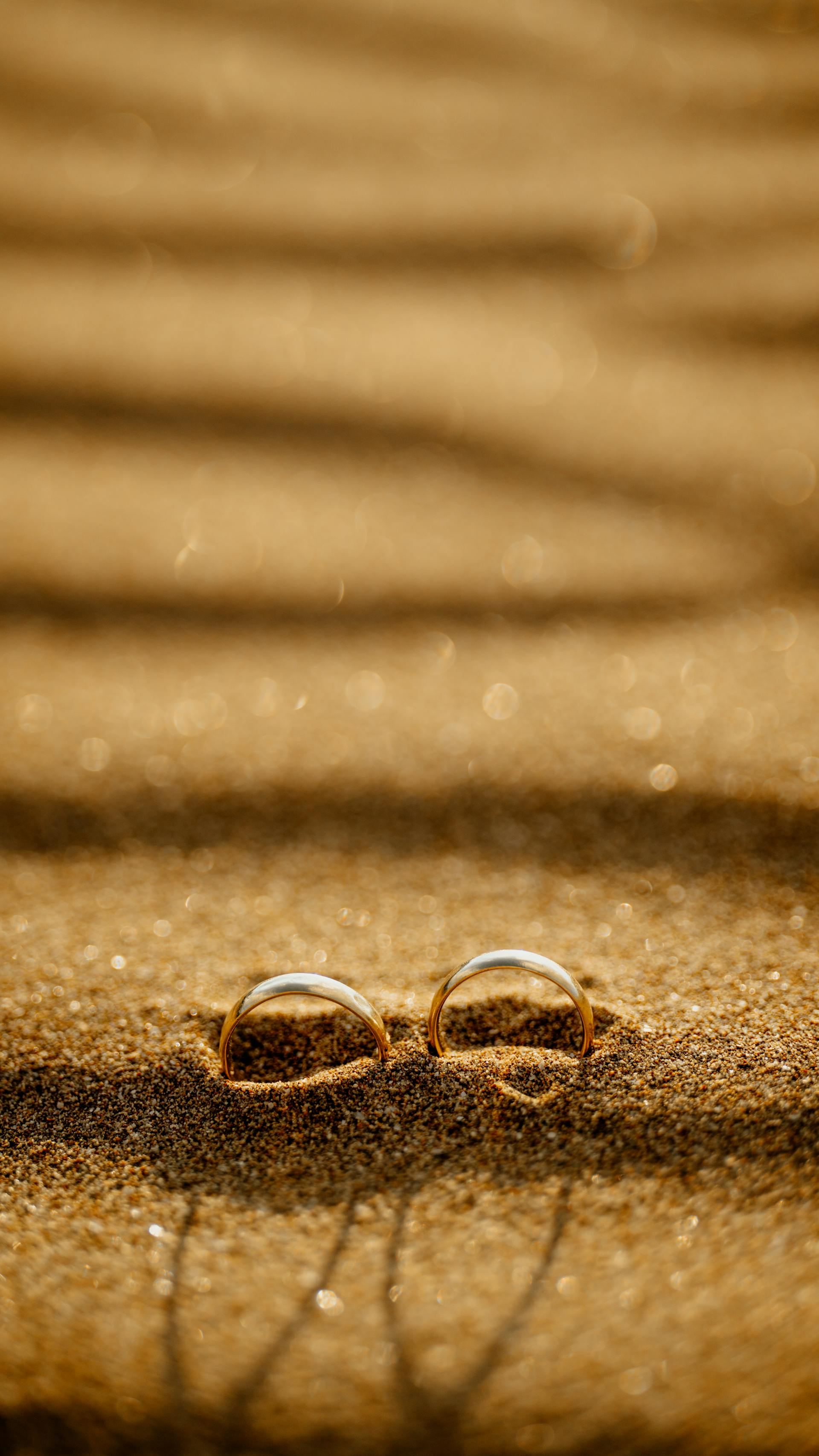 Anillos de boda en una playa de arena al atardecer | Fuente: Pexels