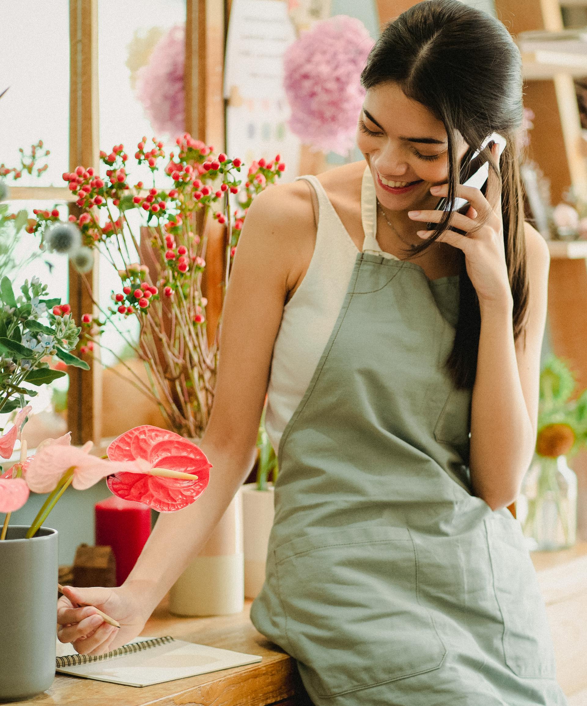 Una mujer feliz con delantal en una llamada | Fuente: Pexels