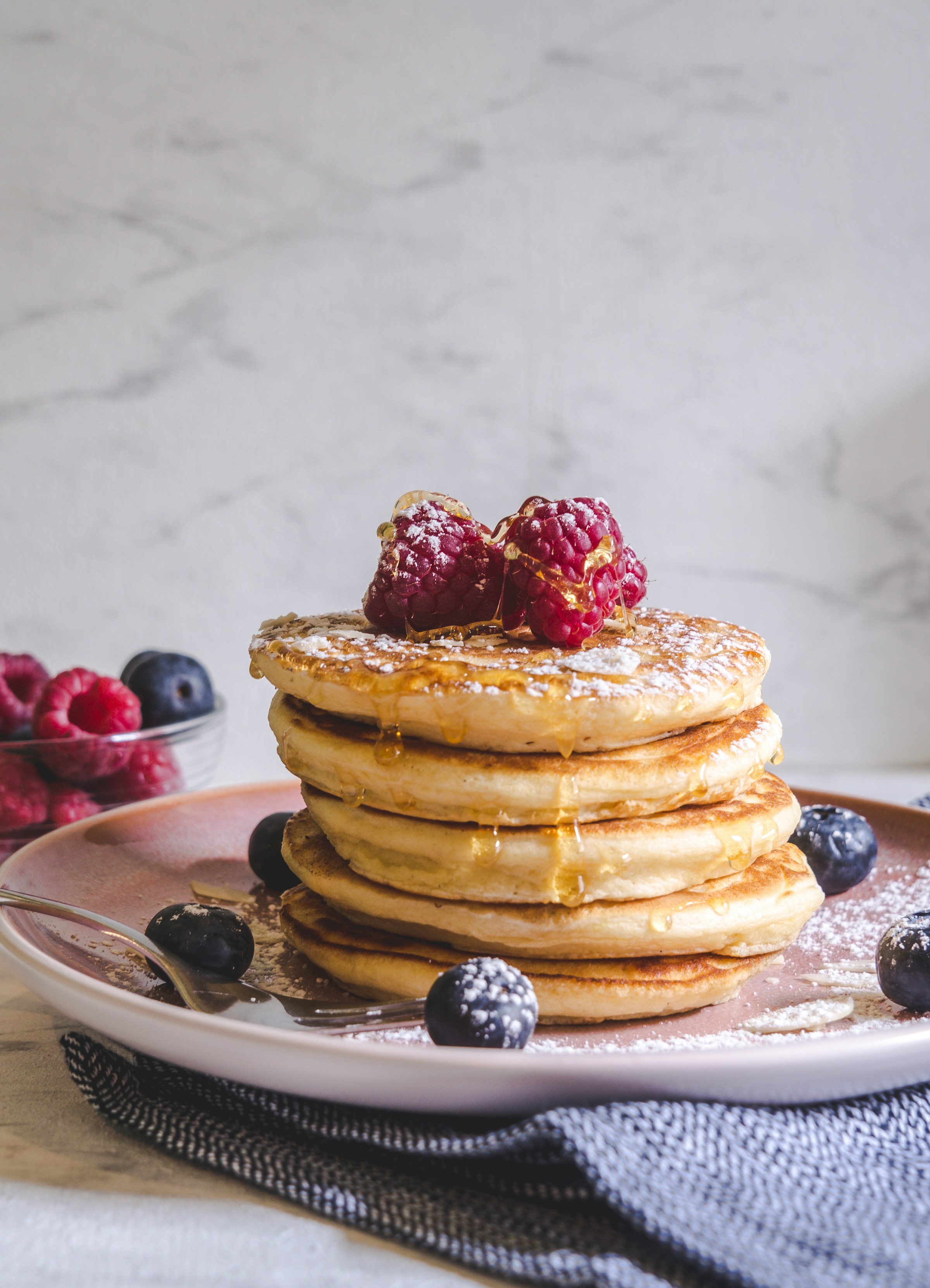 Una foto que muestra panqueques con frutas sobre un plato de cerámica blanca | Fuente: Unsplash