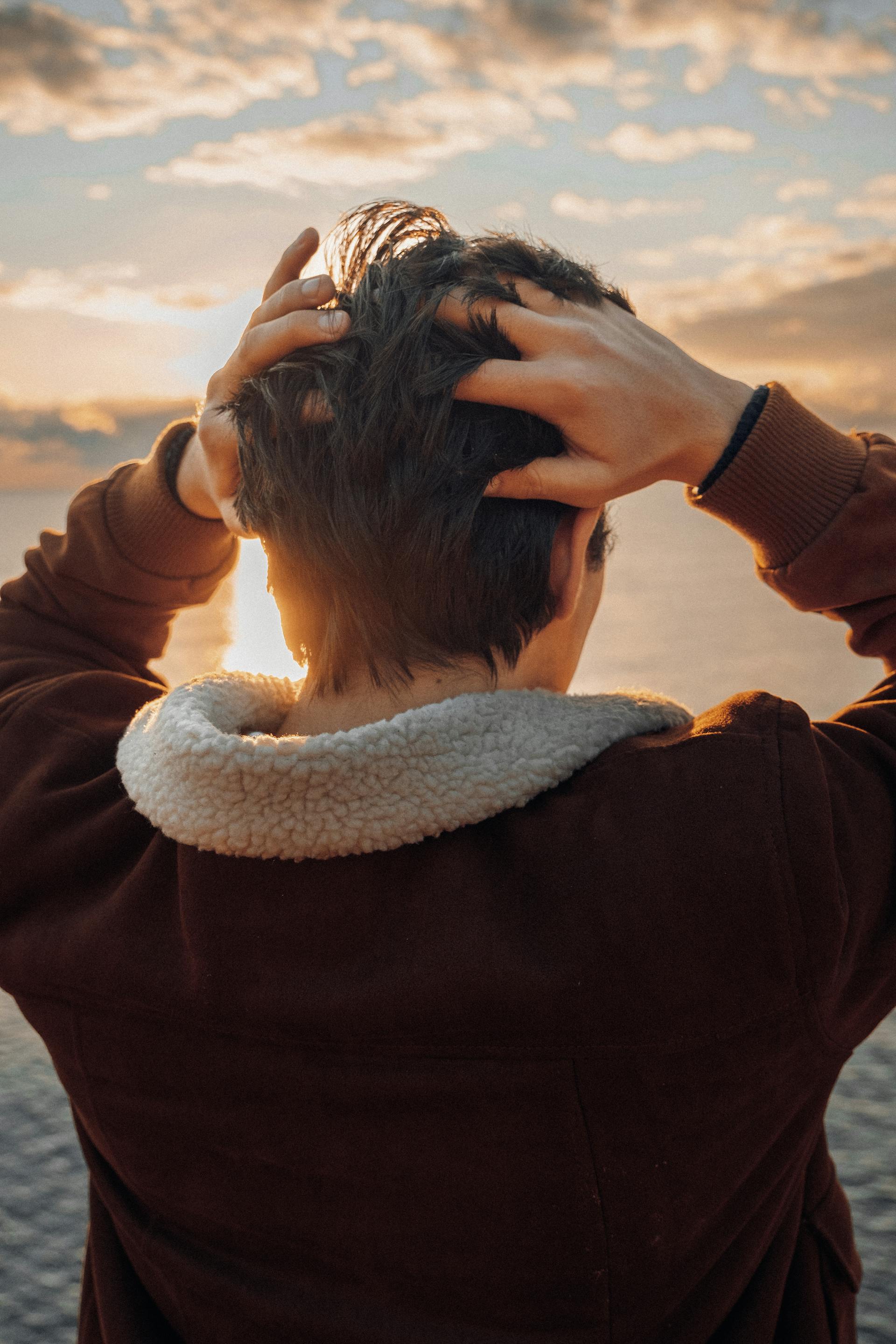 Un joven tocándose la nuca mientras está de pie en la playa | Fuente: Pexels