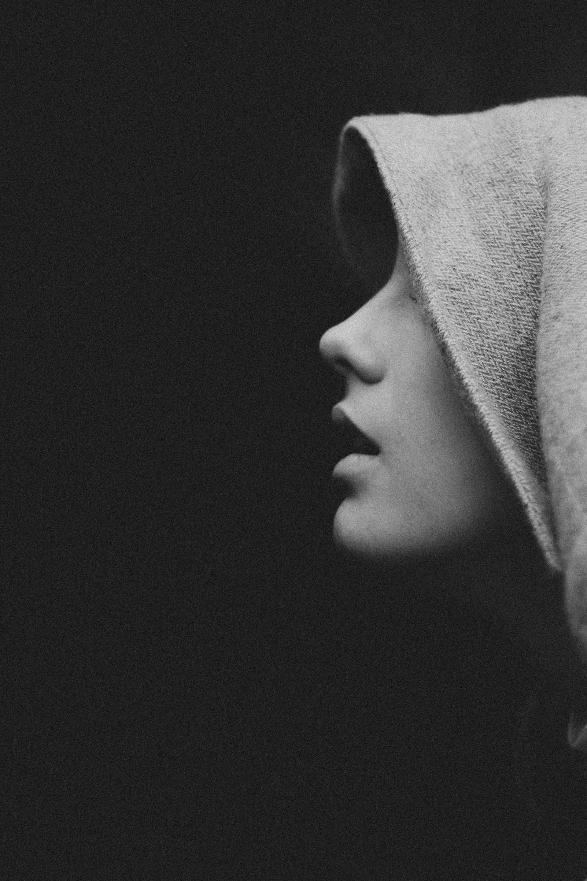 Foto en escala de grises de una joven con sudadera con capucha | Fuente: Pexels