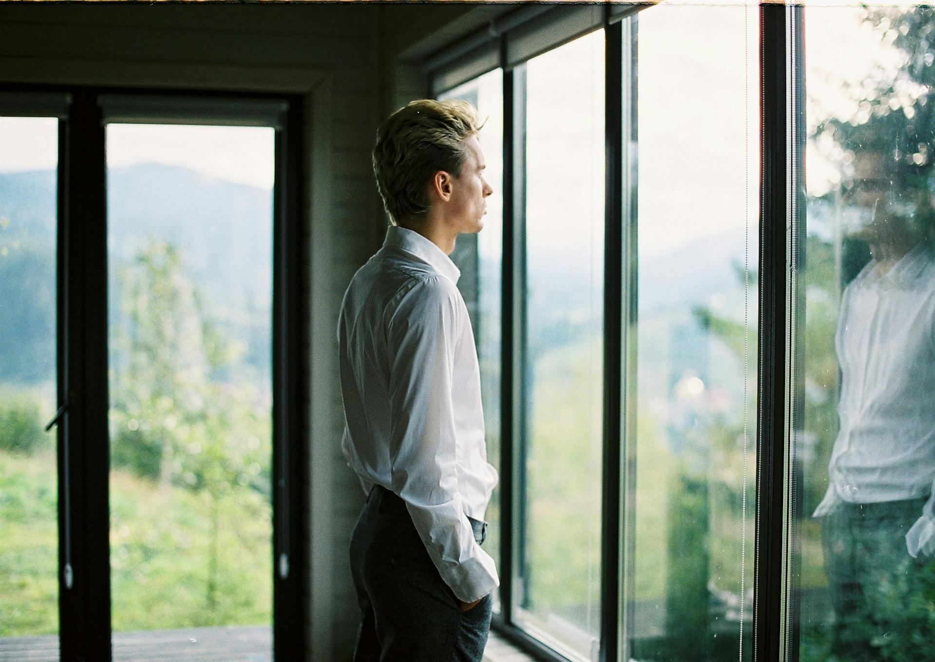 Un hombre de pie cerca de una ventana de cristal | Fuente: Pexels