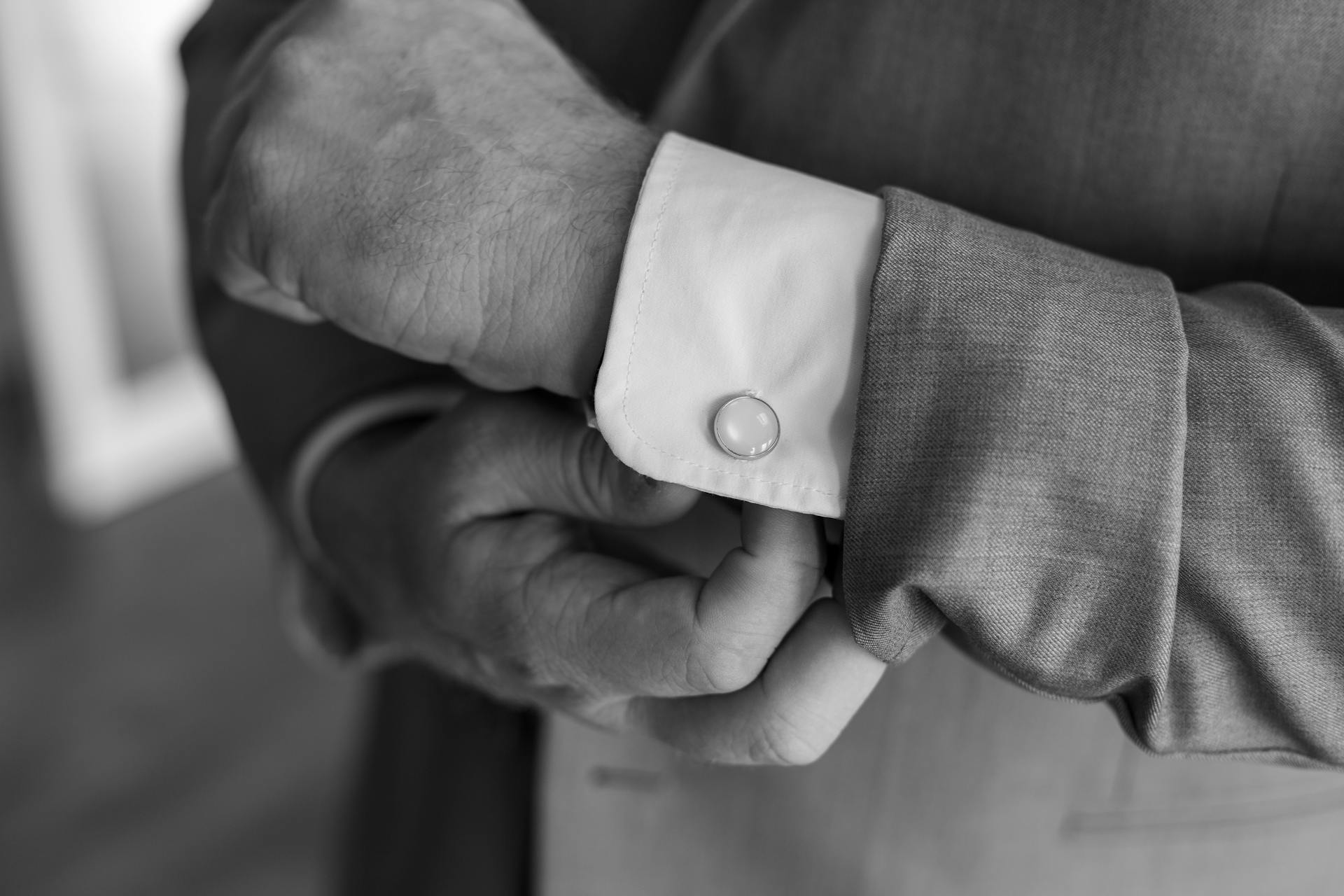Foto en escala de grises de un hombre ajustándose el gemelo | Fuente: Pexels