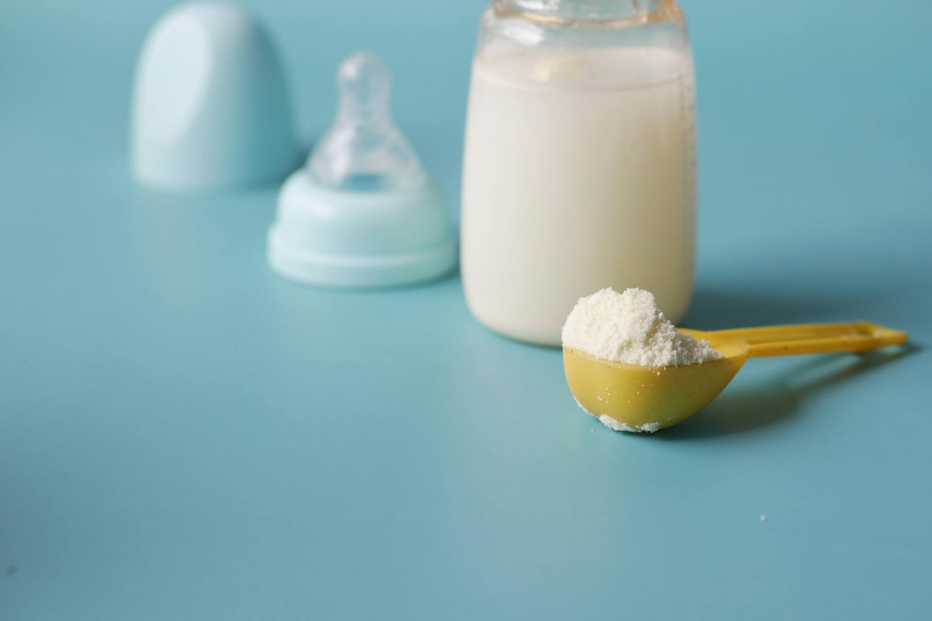 Primer plano del biberón de un bebé y una cucharada de leche de fórmula en polvo | Fuente: Pexels