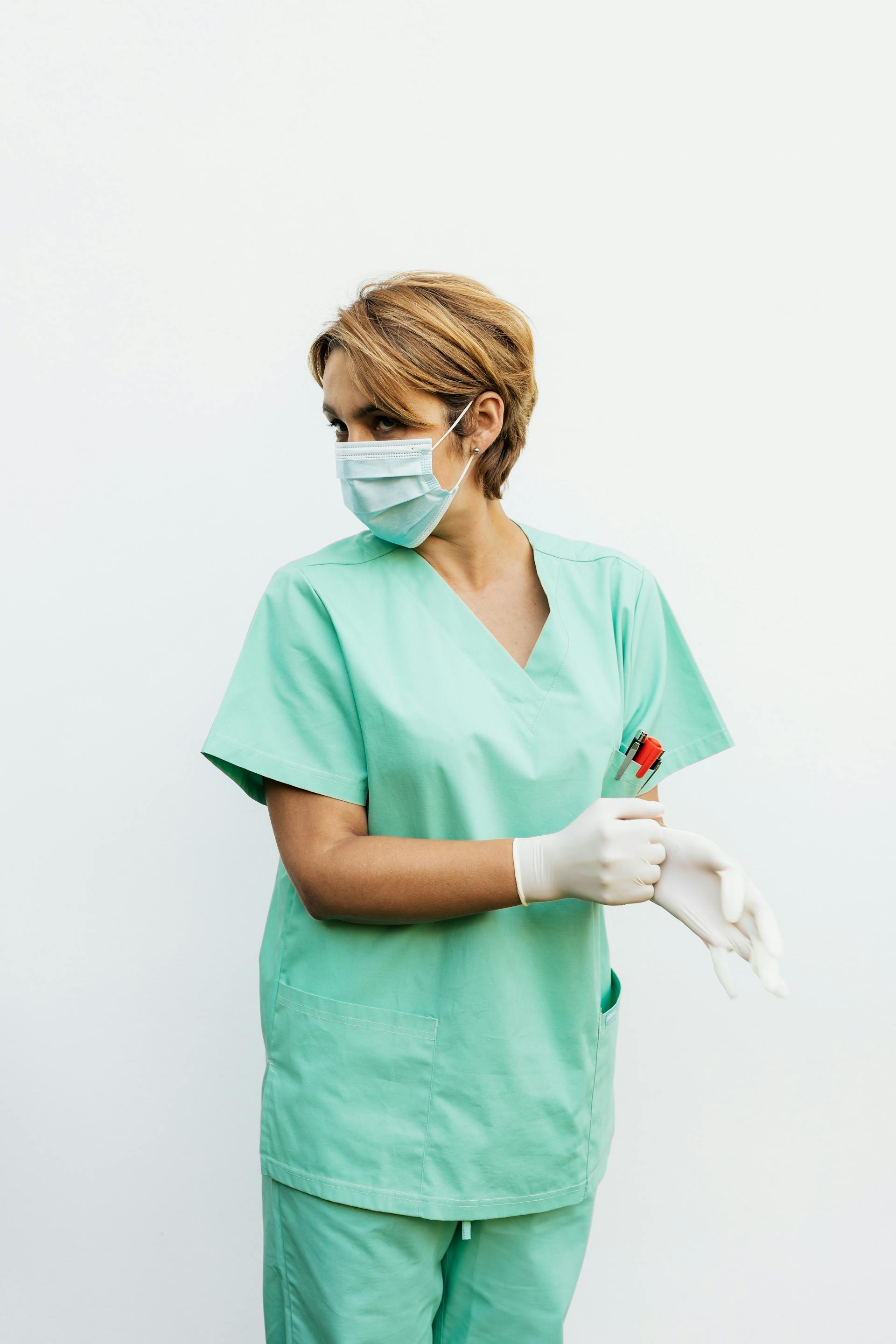 Una enfermera con bata y mascarilla mirando hacia atrás | Fuente: Pexels