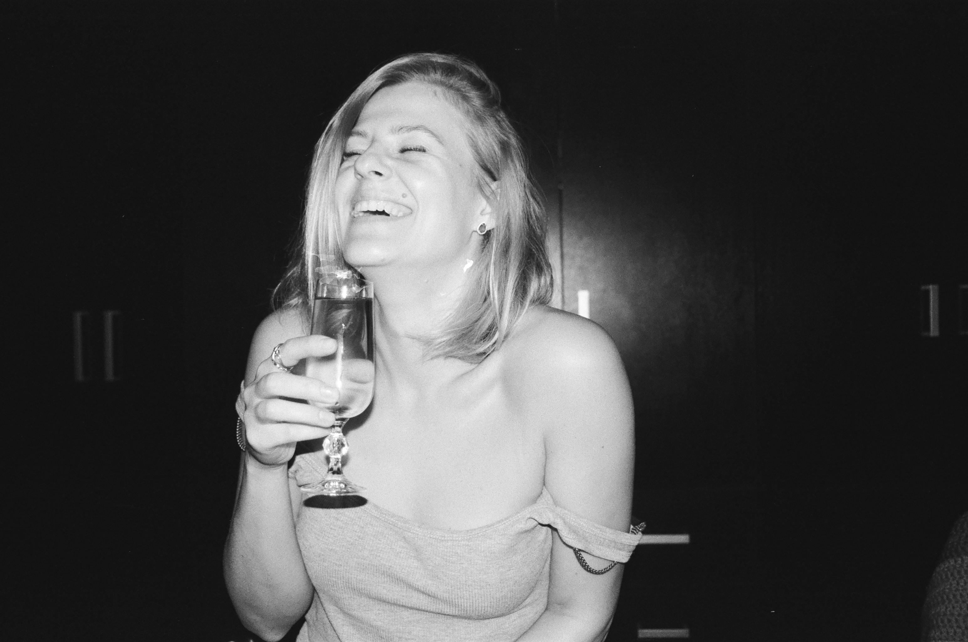 Una mujer riendo mientras sostiene un vaso | Fuente: Pexels