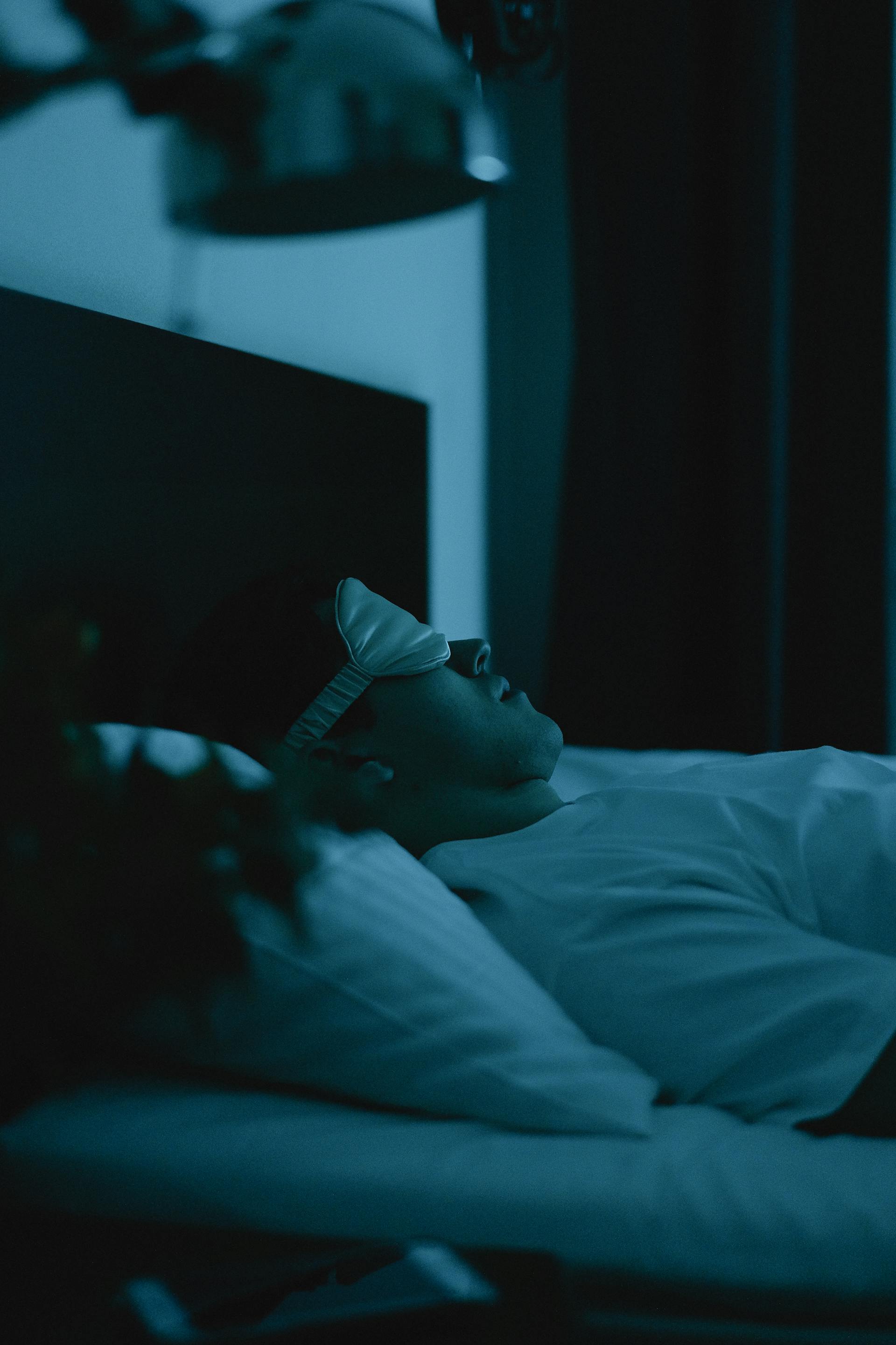 Un hombre con un antifaz para dormir tumbado en la cama | Fuente: Pexels