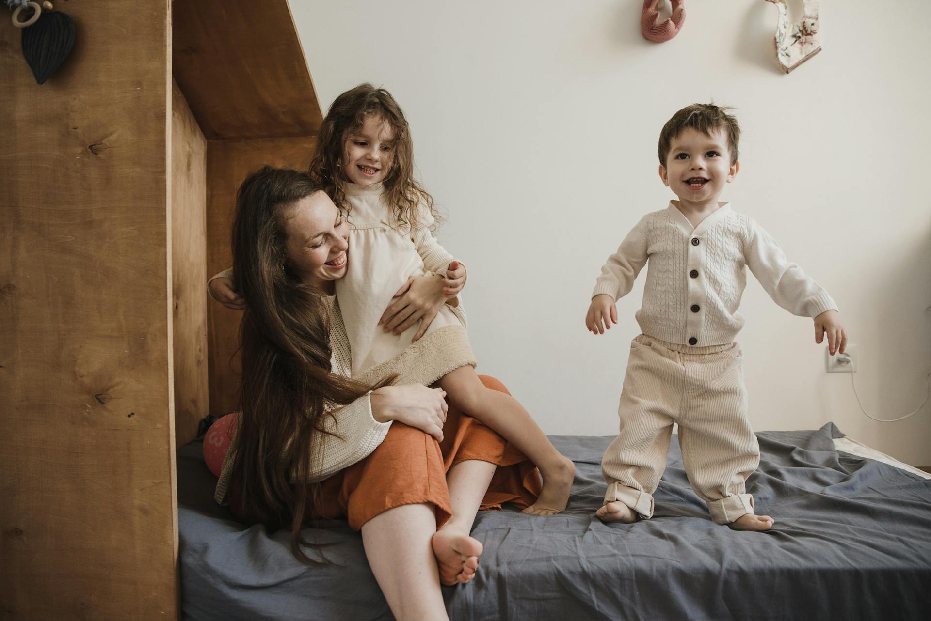 Una mujer jugando con sus hijos en la cama | Fuente: Pexels