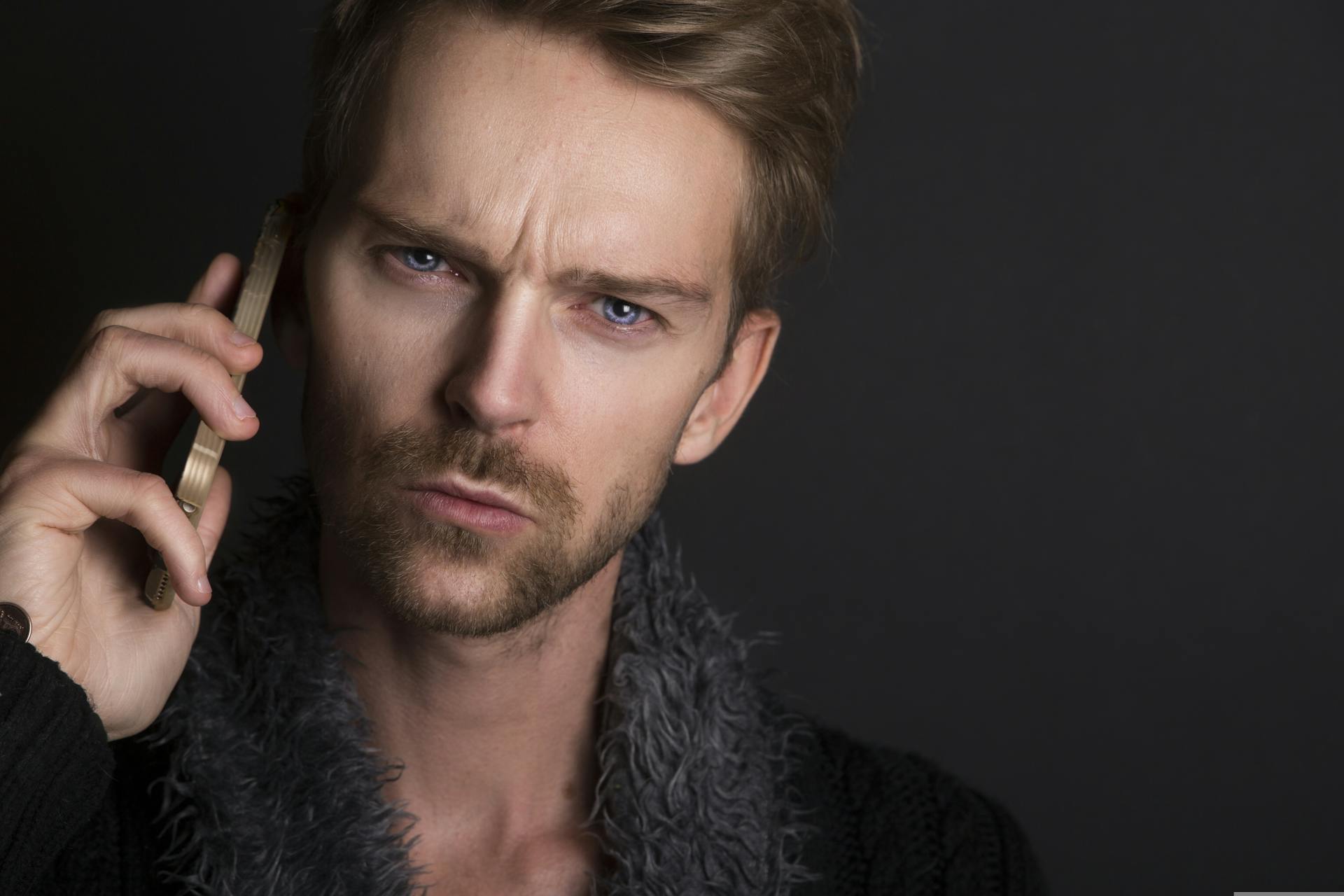 Un hombre de ojos azules y ceño fruncido hablando por teléfono | Fuente: Pexels