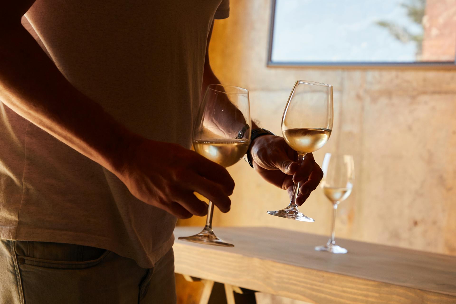 Un hombre sujetando copas de vino | Fuente: Pexels