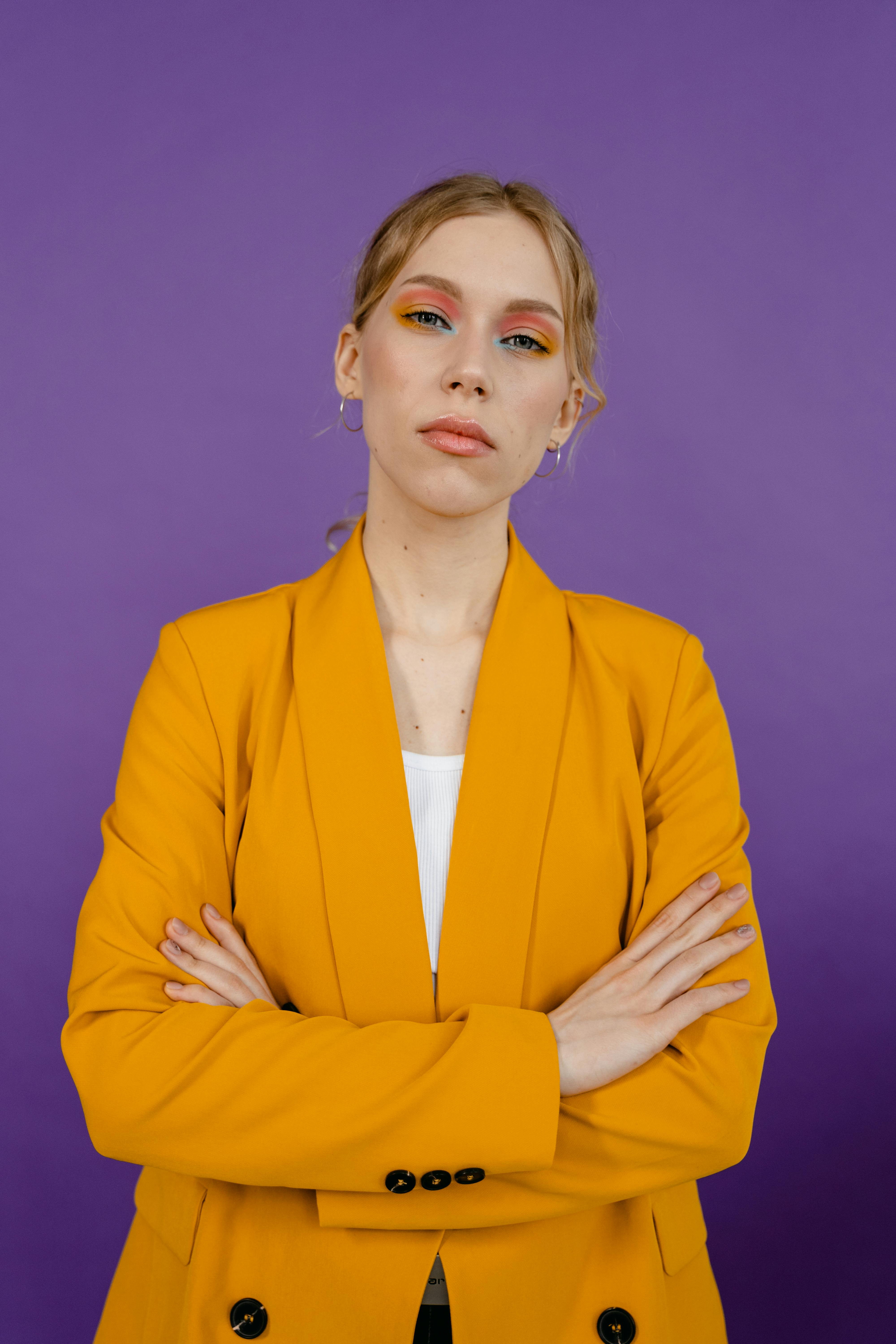 Mujer frustrada con traje amarillo cruzada de brazos | Fuente: Pexels