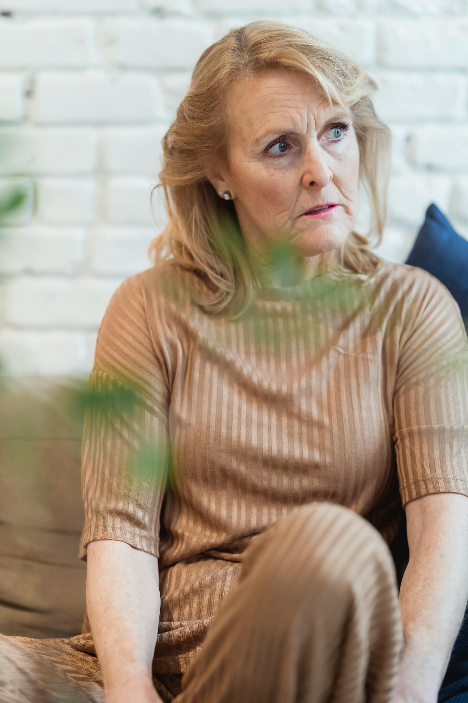 Una mujer de mediana edad pensativa sentada en el sofá | Fuente: Pexels