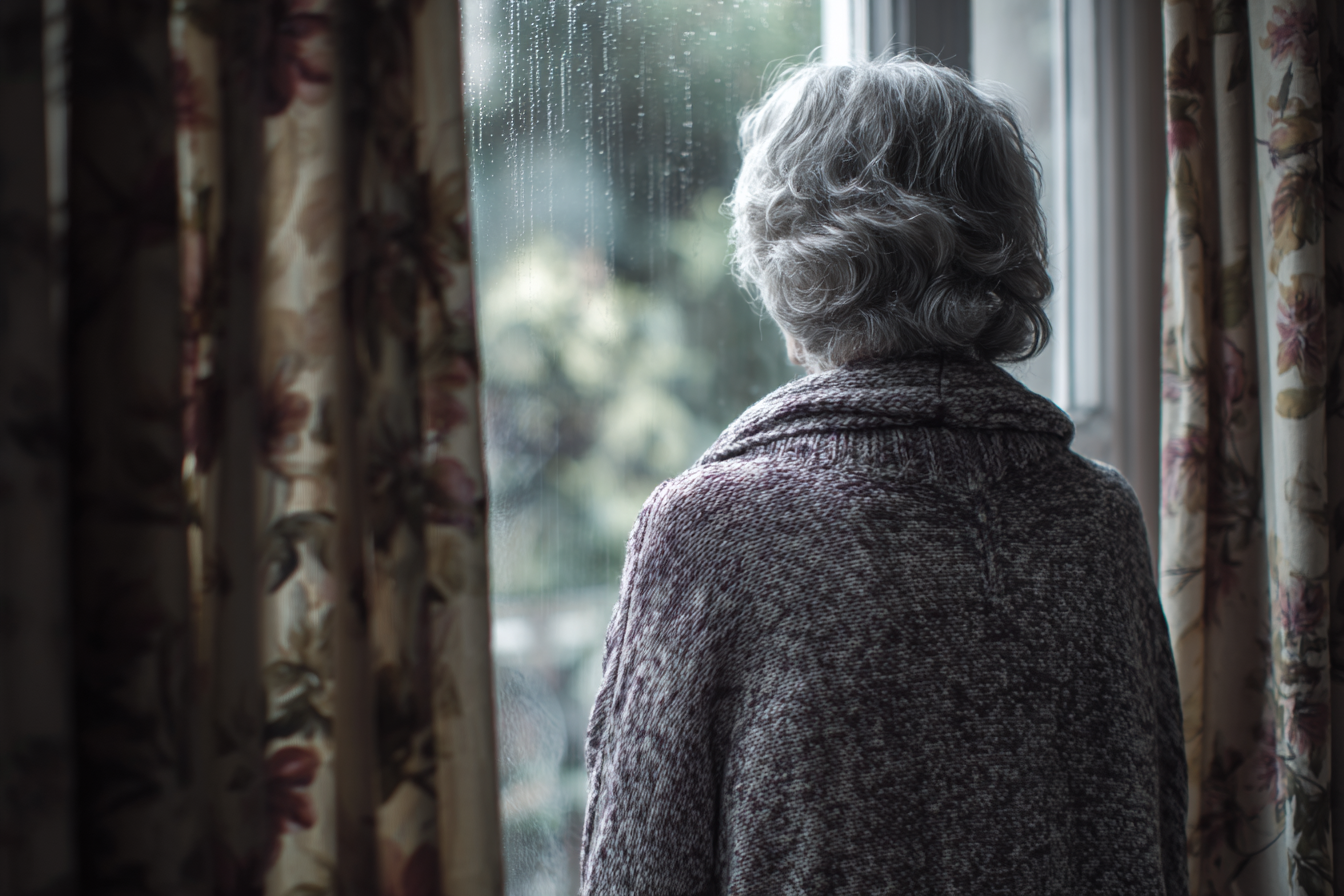 Una mujer mayor junto a una ventana | Fuente: Midjourney
