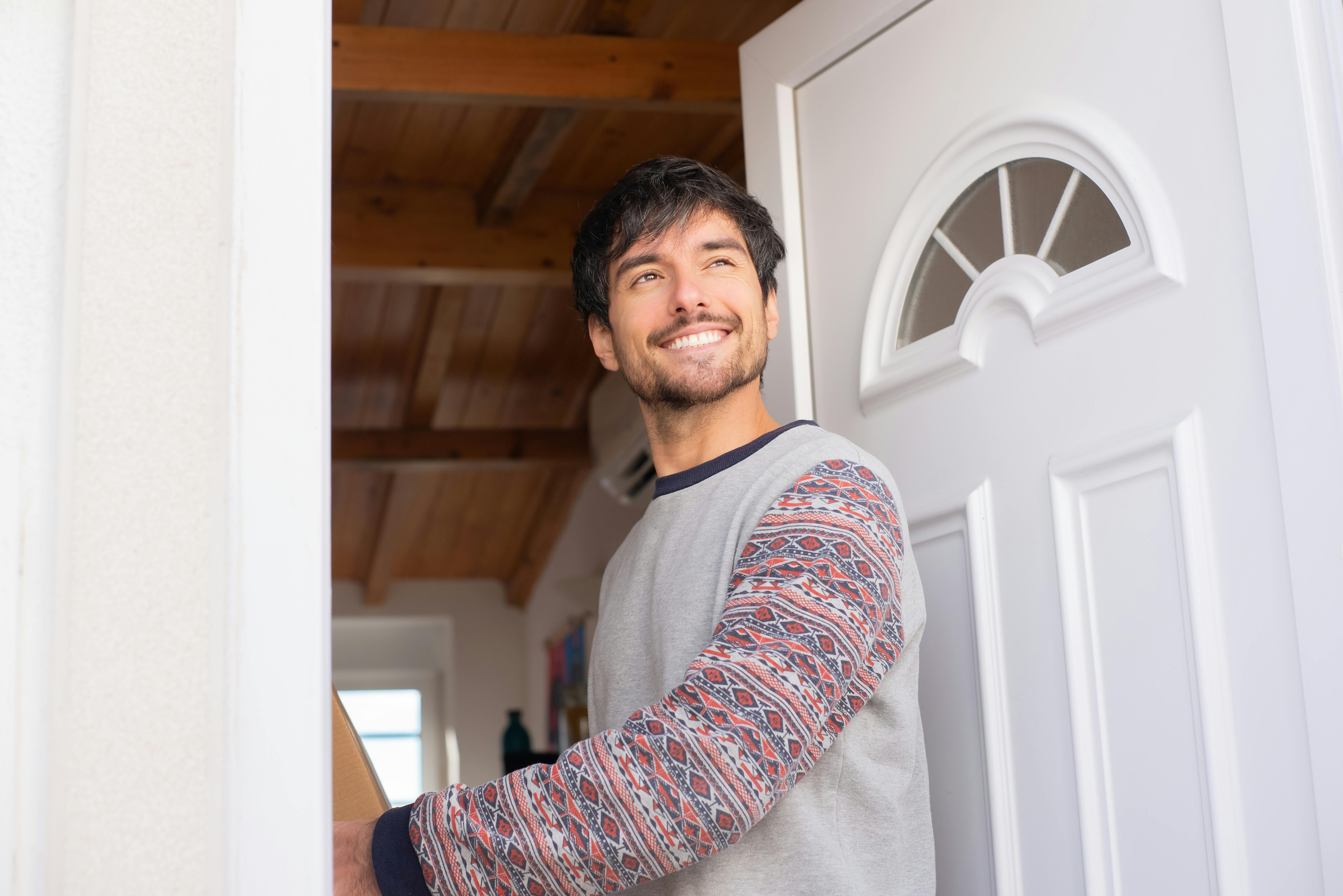 Un hombre sonriendo de pie en la puerta | Fuente: Pexels