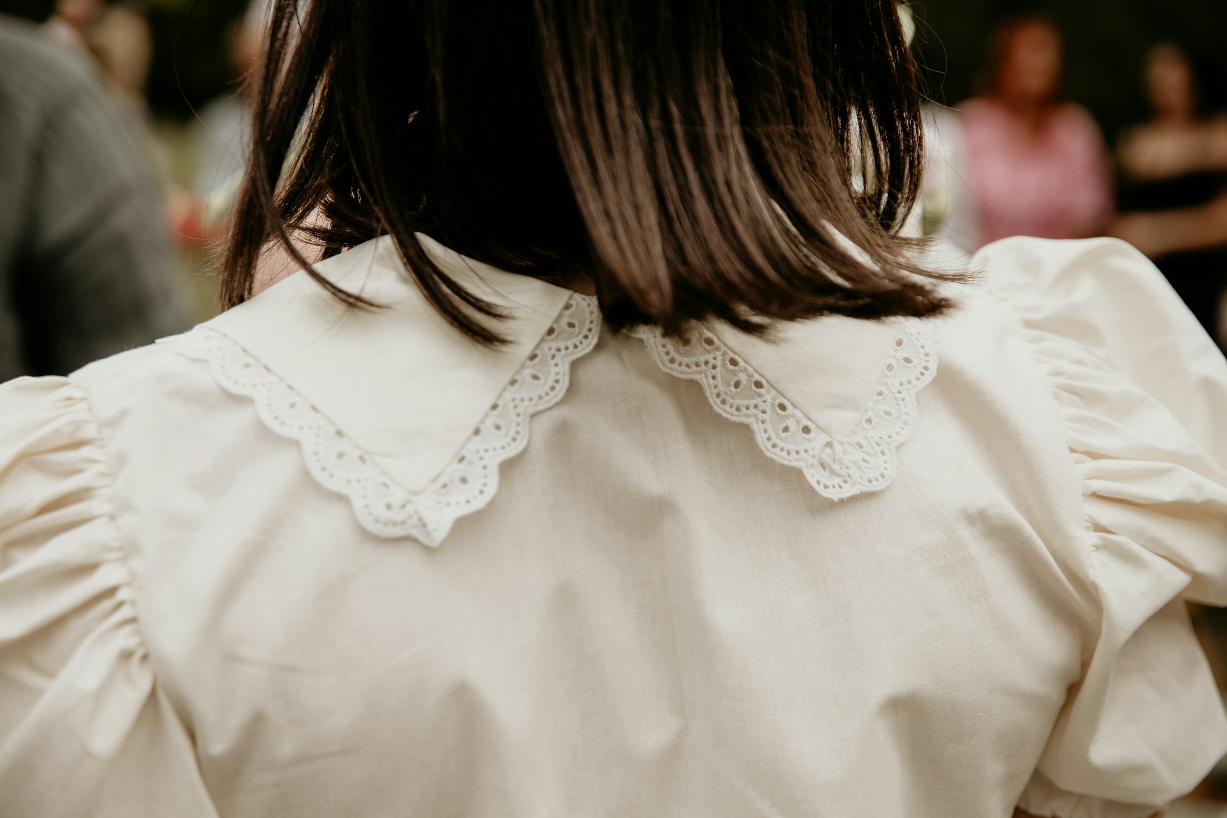 Una toma de espaldas de una mujer que lleva una blusa blanca con cuello festoneado | Fuente: Unsplash