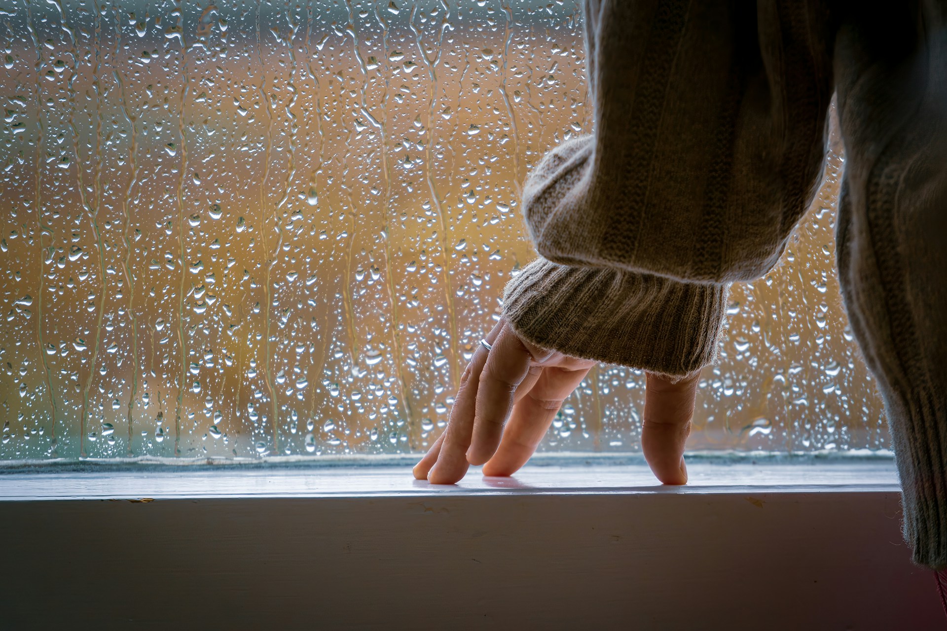 Una mujer de pie cerca de una ventana observando la lluvia | Fuente: Unsplash