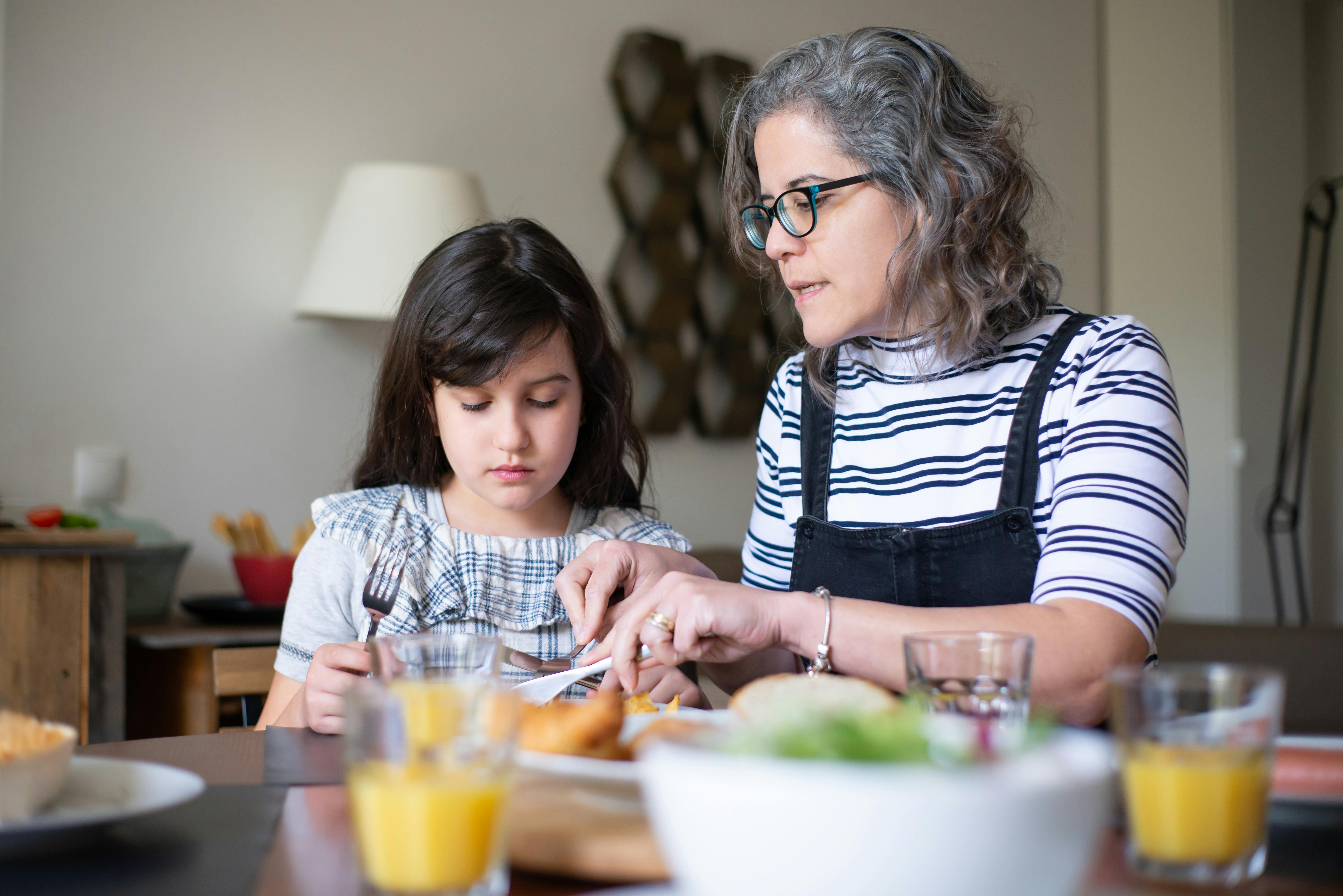 Mujer hablando con una niña en una mesa | Fuente: Pexels