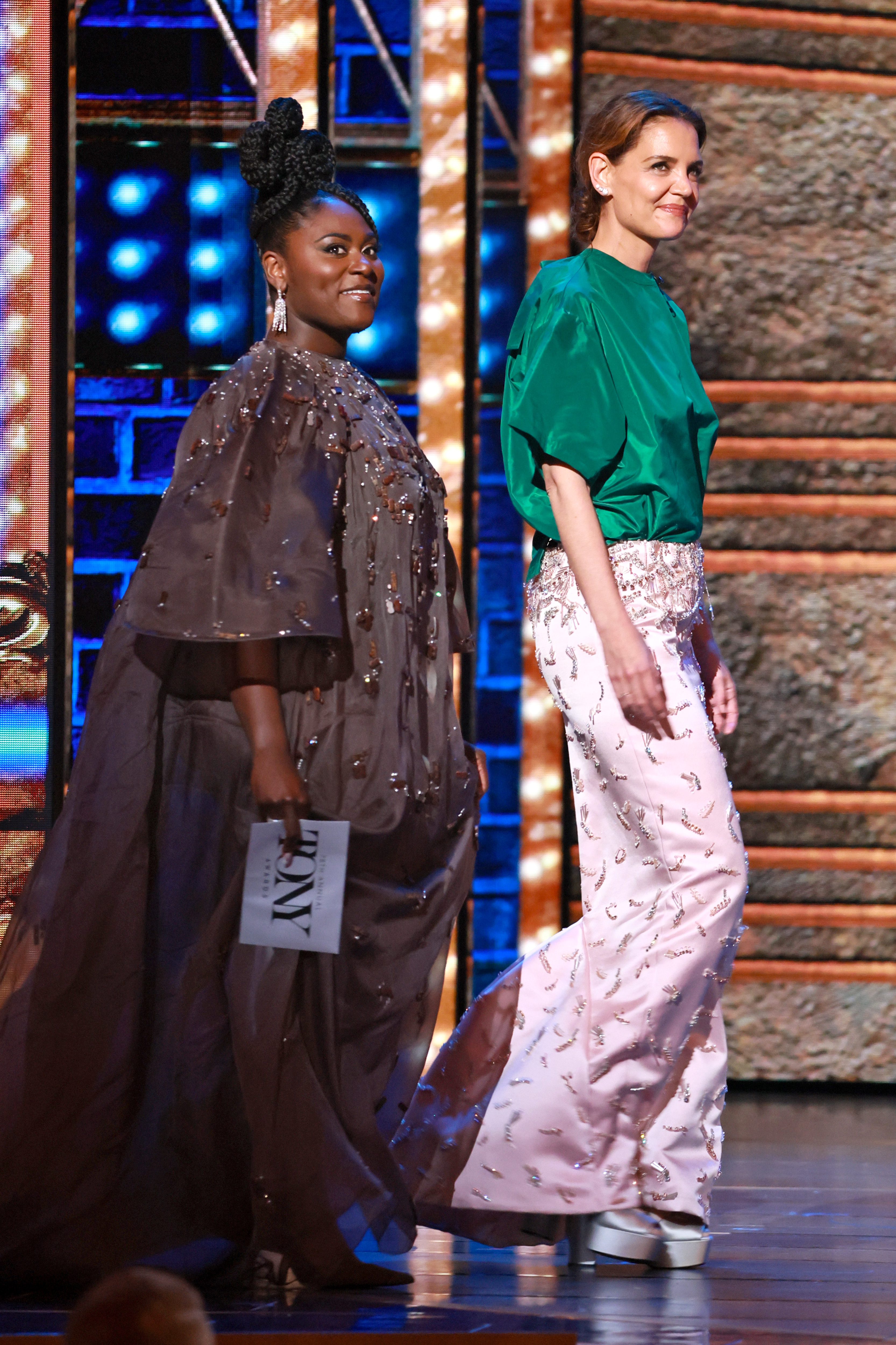 Katie Holmes camina por el escenario junto a Danielle Brooks durante la 78.ª edición de los Premios Tony, presentando con aplomo y una sonrisa un atrevido top verde y una falda rosa suave en el Radio City Music Hall el 8 de junio de 2025.