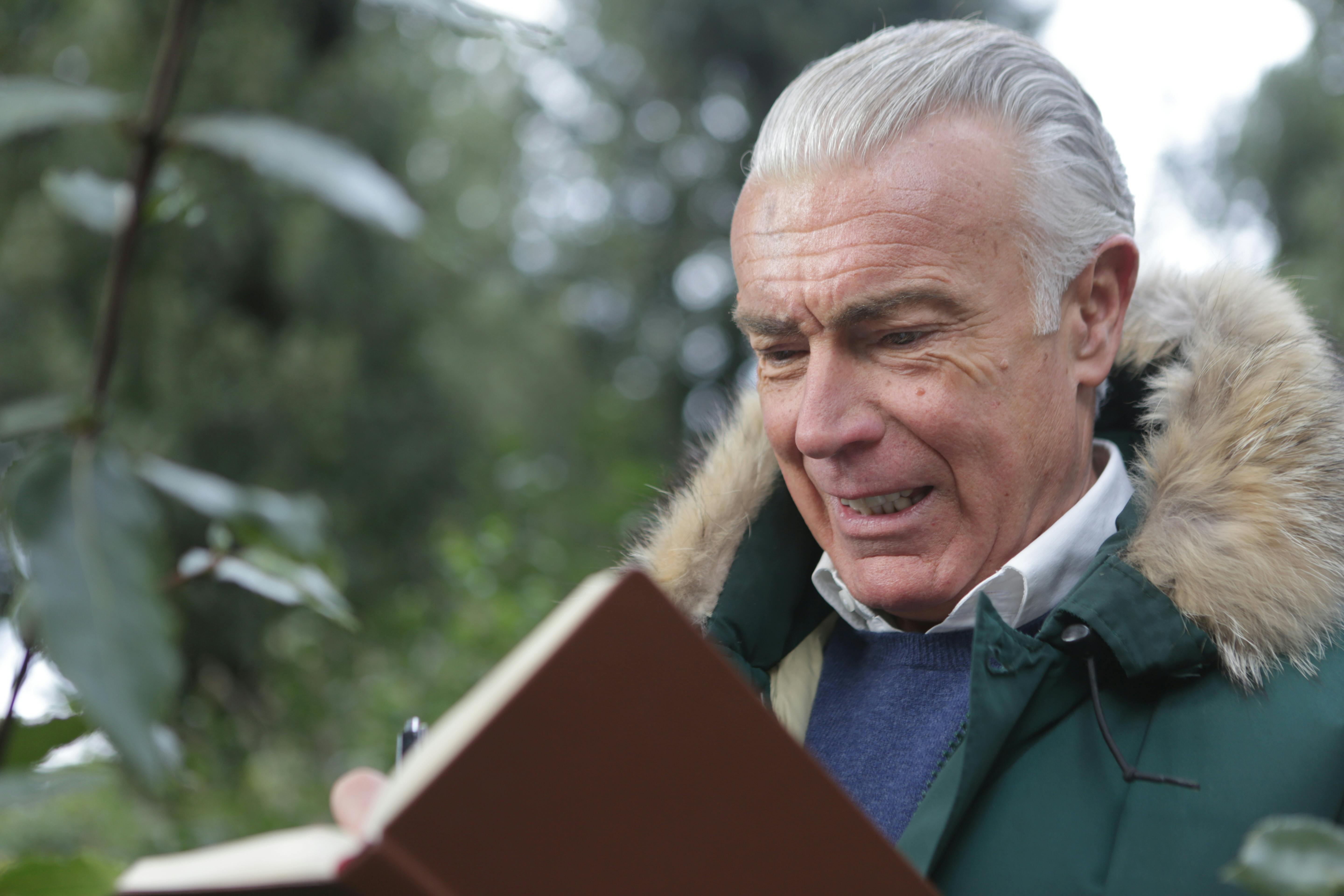 Un hombre mayor con un libro abierto delante de él | Fuente: Pexels