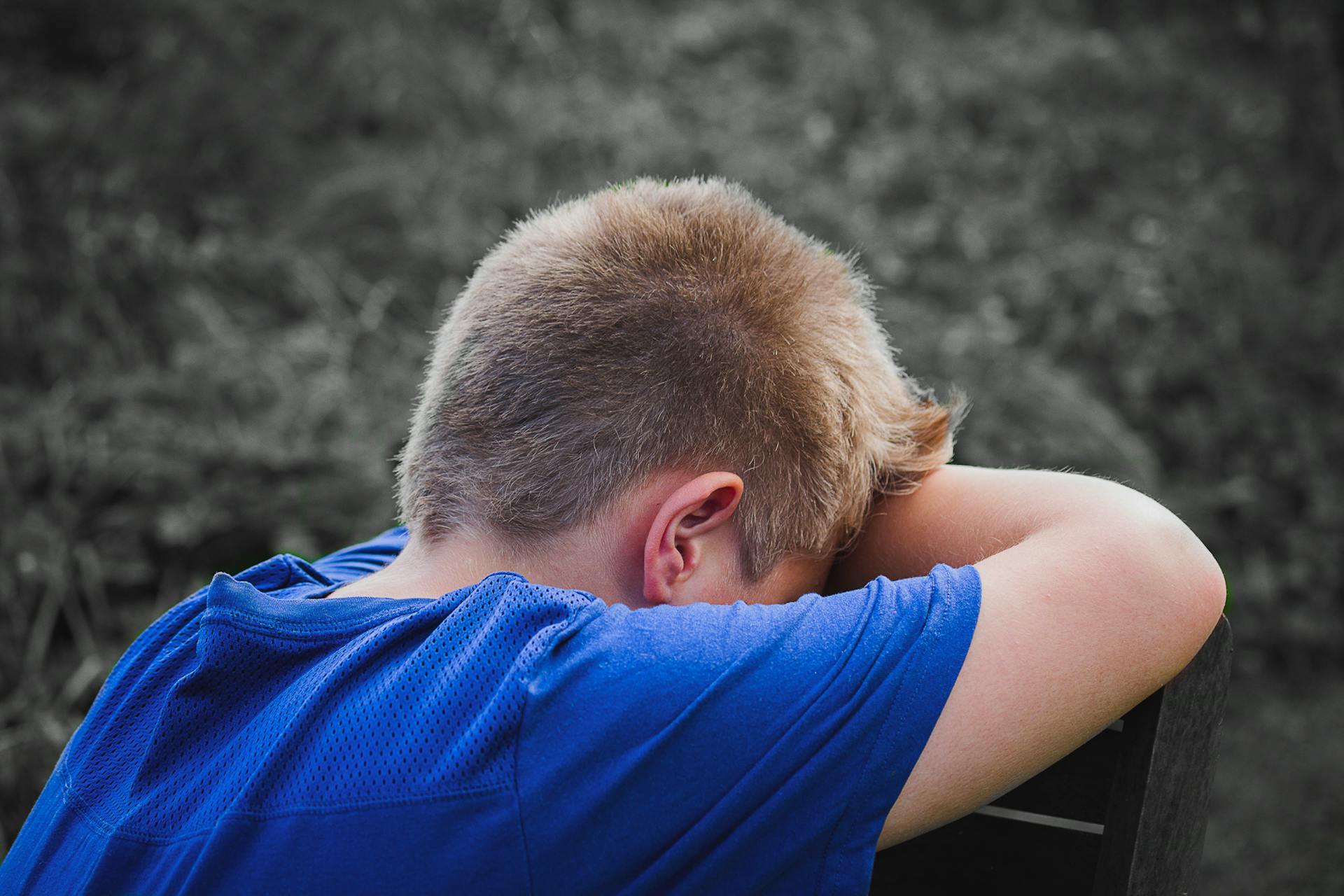 Un niño triste apoyado en una silla de madera | Fuente: Pexels