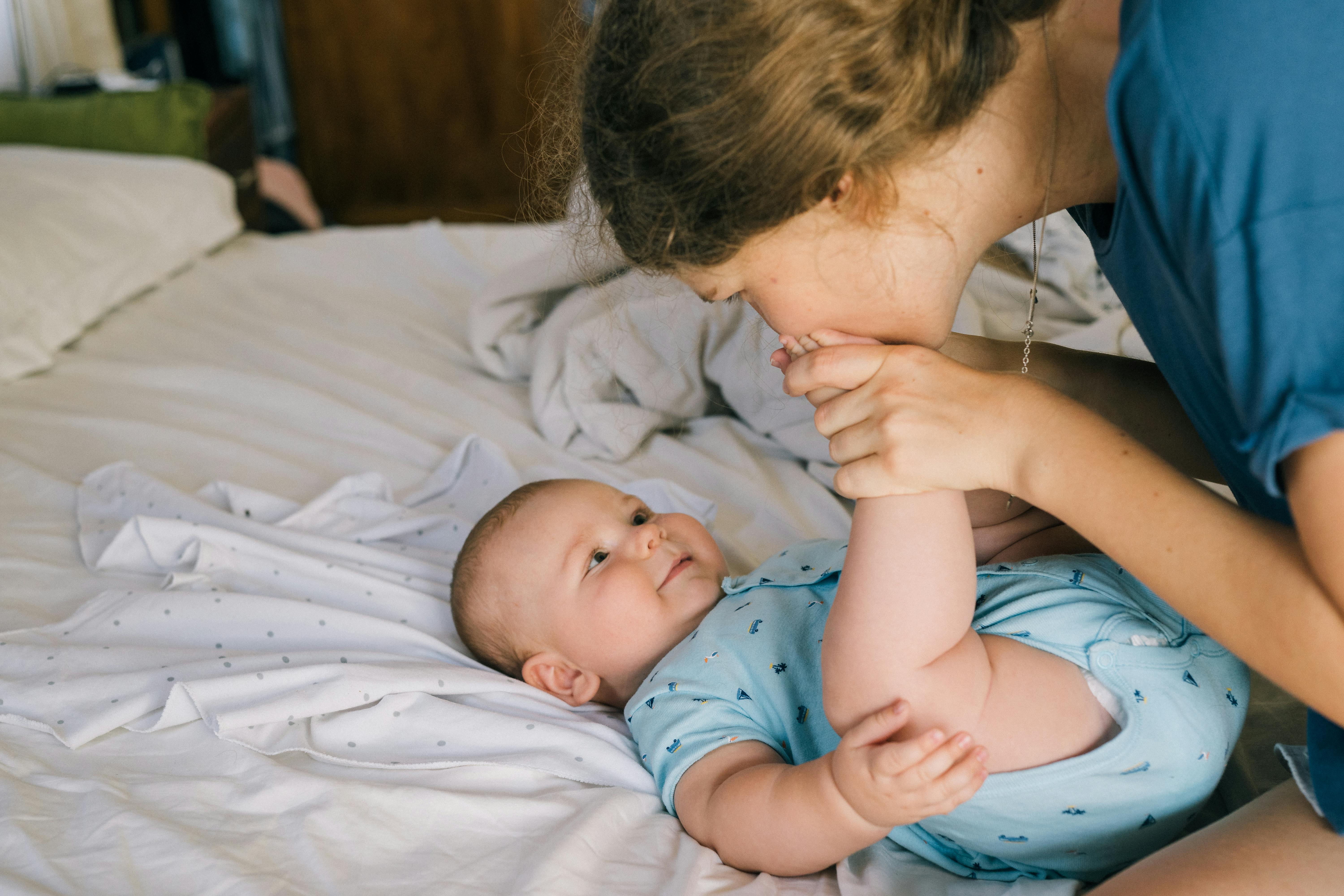 Mujer besando los pies de su bebé | Fuente: Pexels