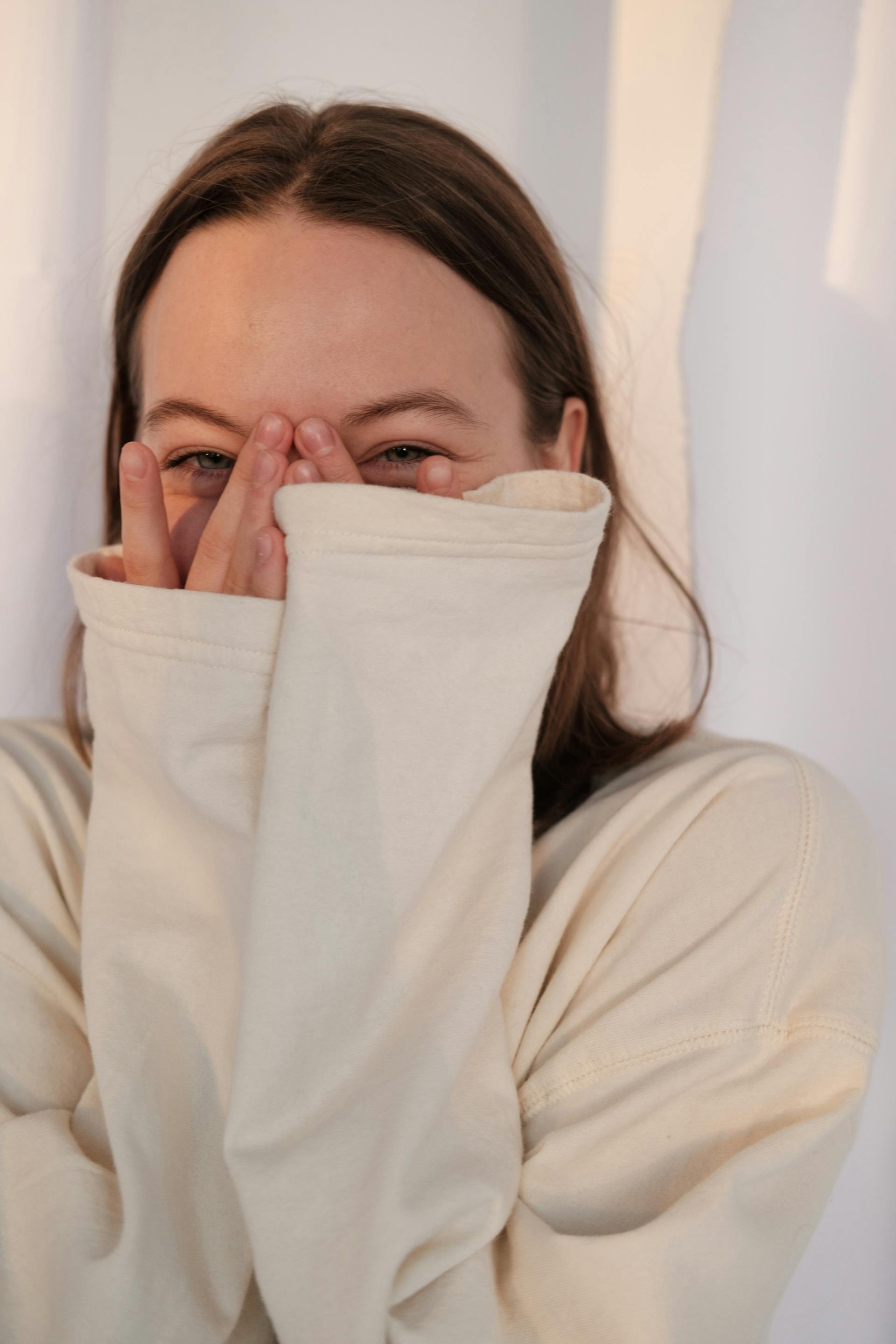 Una mujer divertida mirando entre sus dedos | Fuente: Pexels