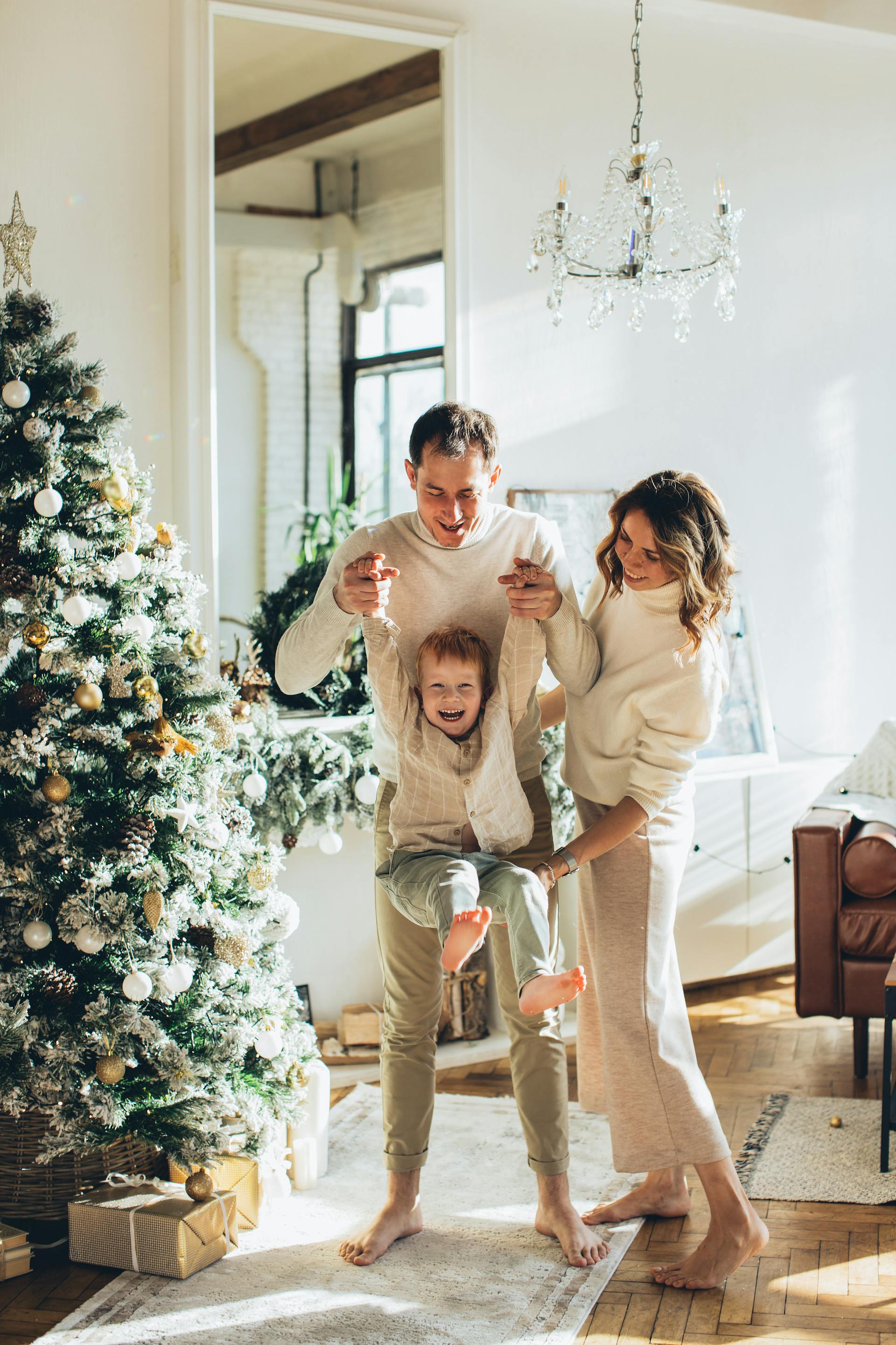 Una pareja juega con su hijo pequeño junto a un árbol de Navidad | Fuente: Pexels