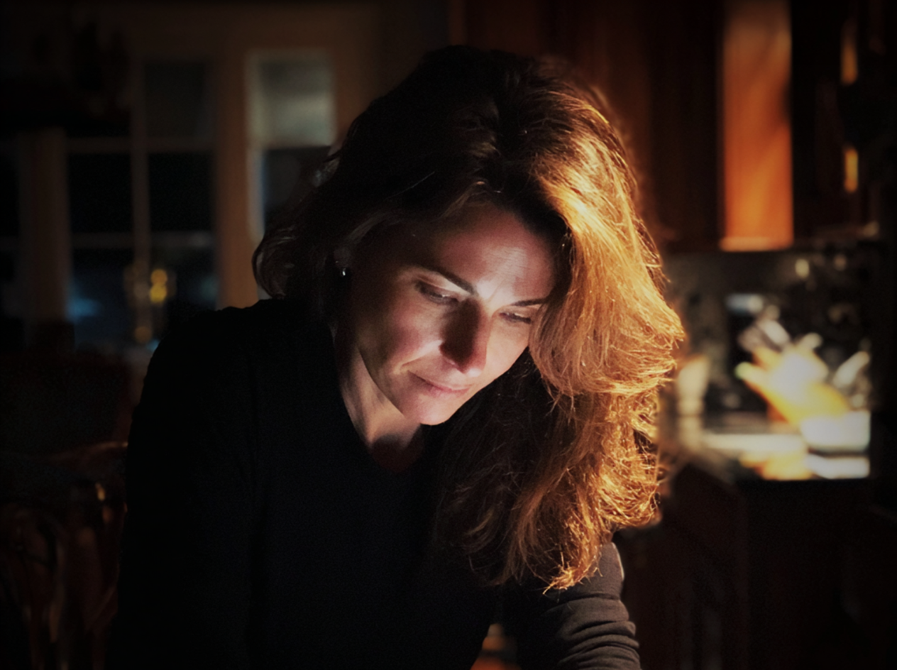 Una mujer sentada a la mesa de la cocina por la noche | Fuente: Midjourney