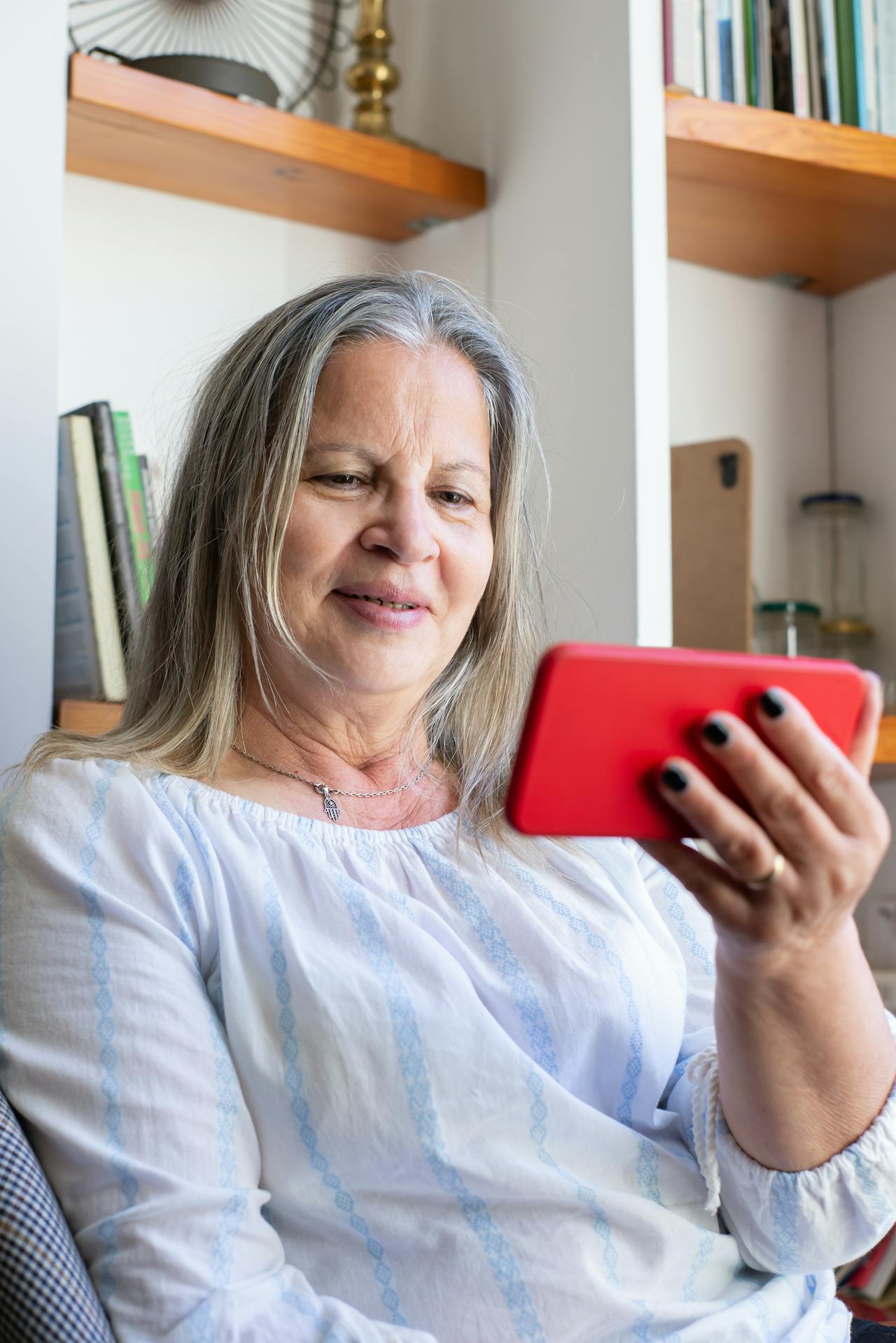 Una mujer mayor mirando su teléfono y sonriendo | Fuente: Pexels