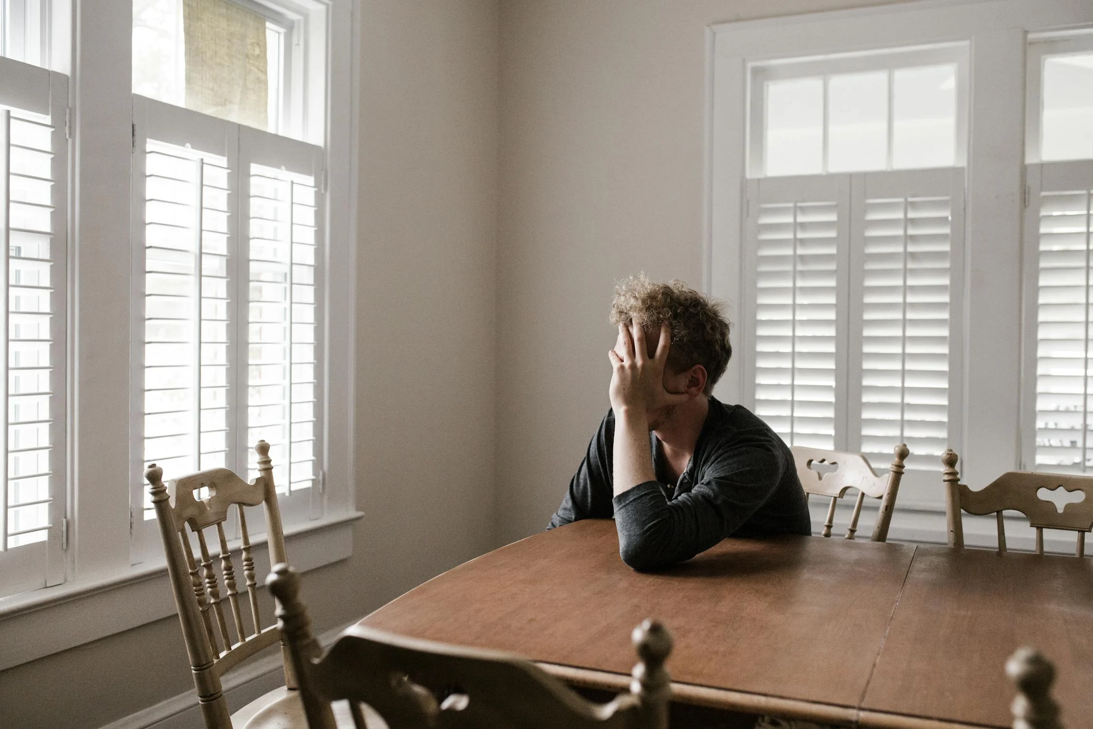 Un hombre triste mirando por la ventana | Fuente: Pexels