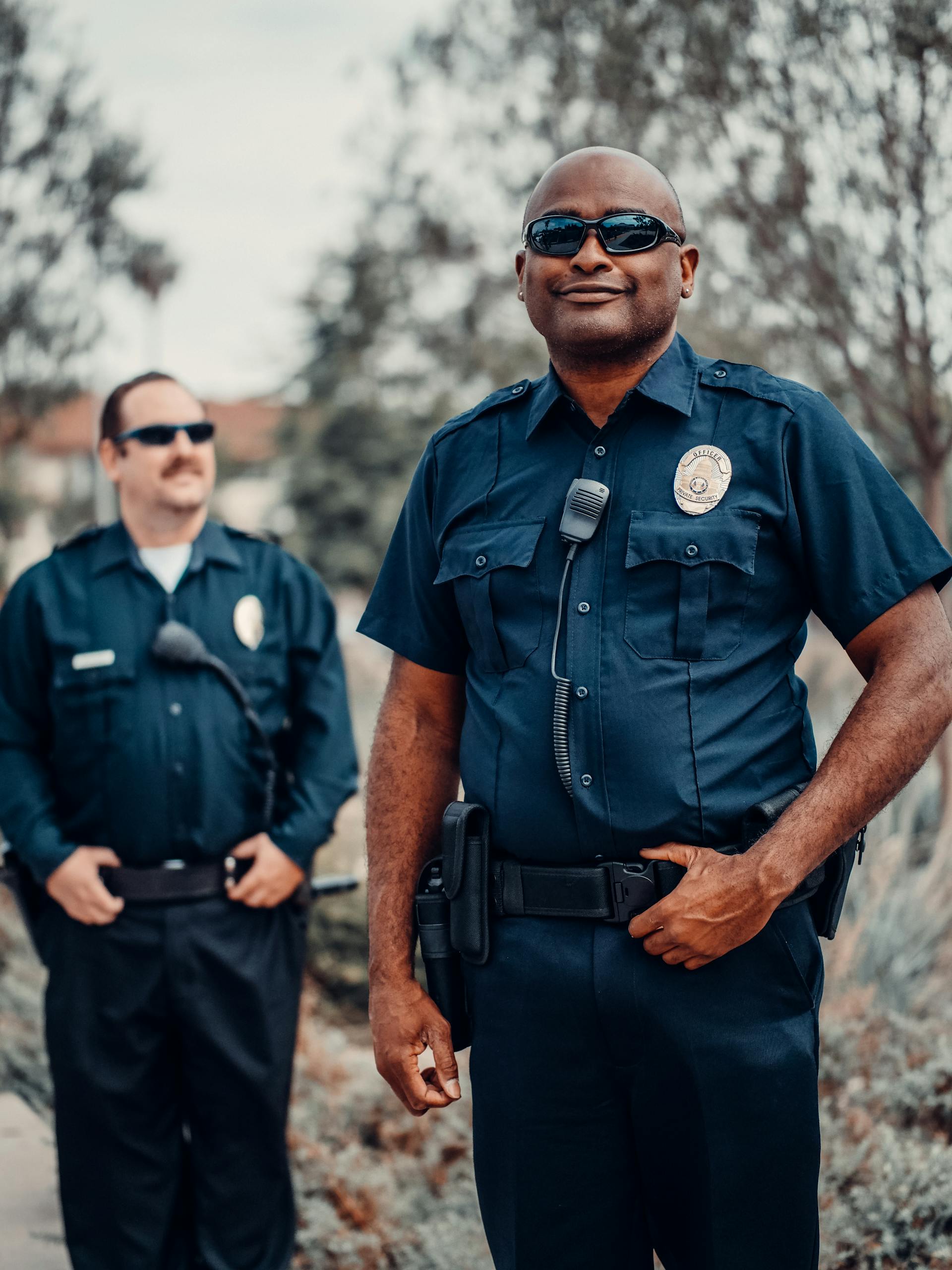 Dos policías sonrientes con uniforme y gafas de sol | Fuente: Pexels