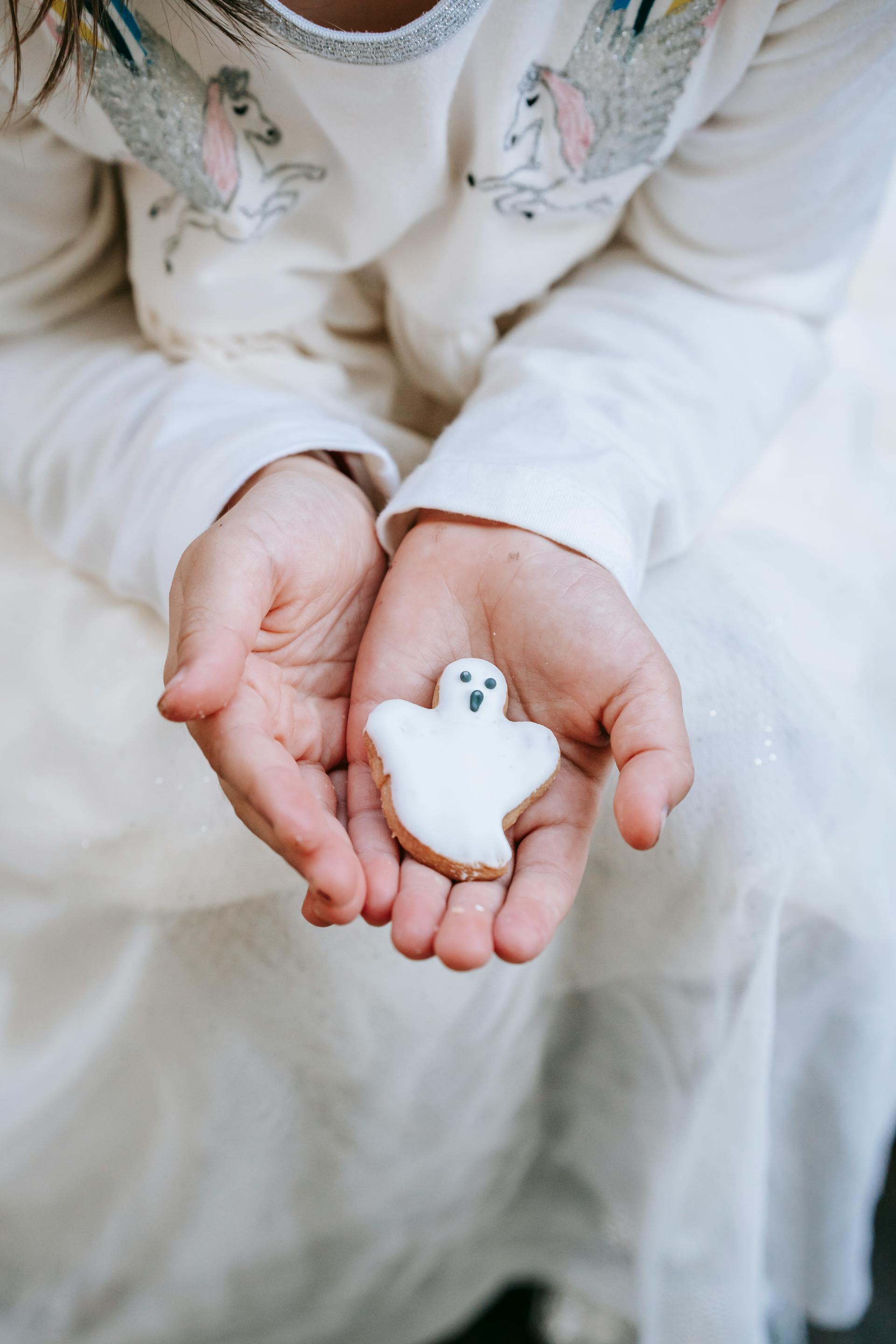 Una niña con una galleta fantasma en las manos | Fuente: Pexels