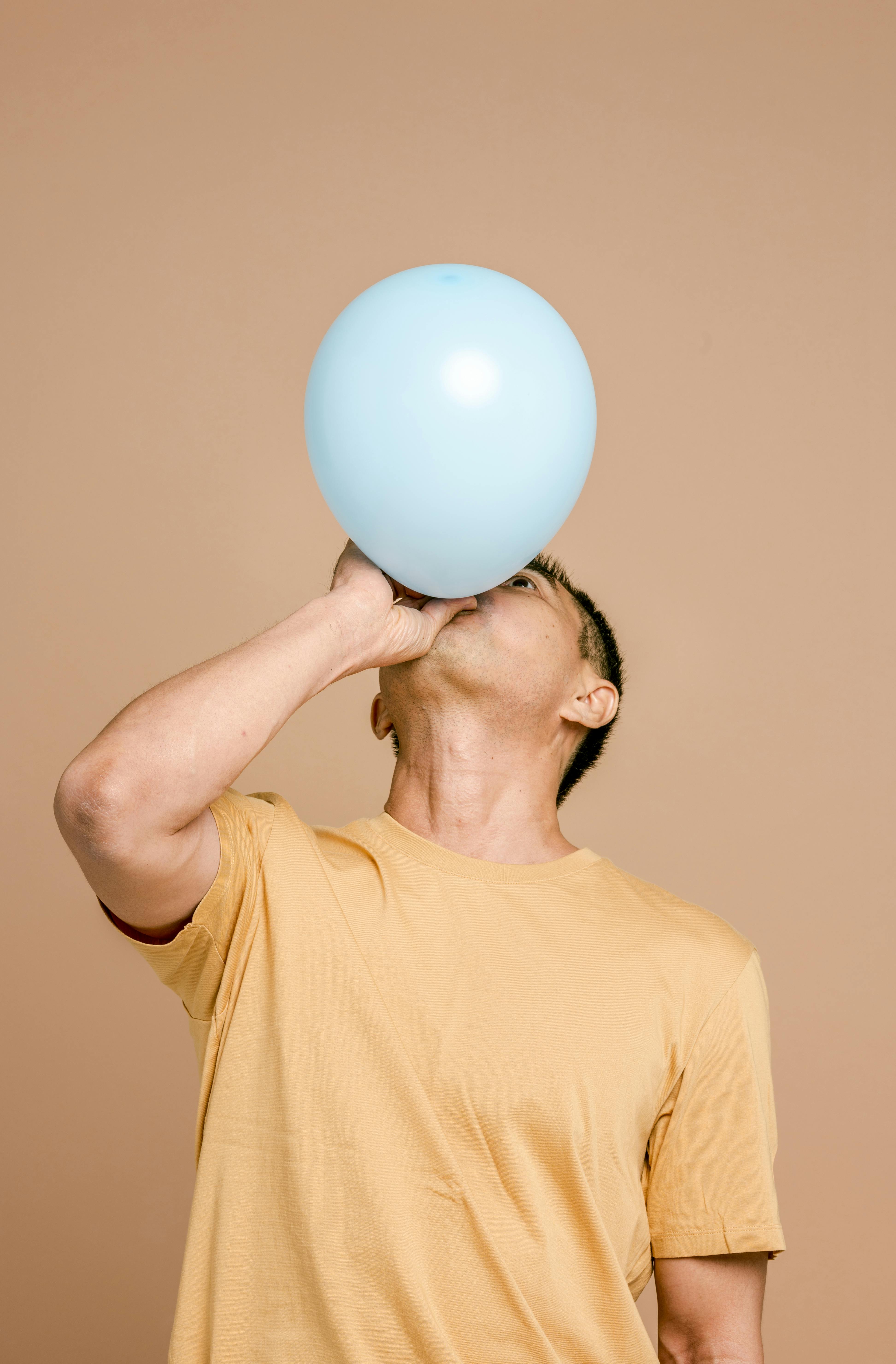 Un hombre inflando un globo | Fuente: Pexels