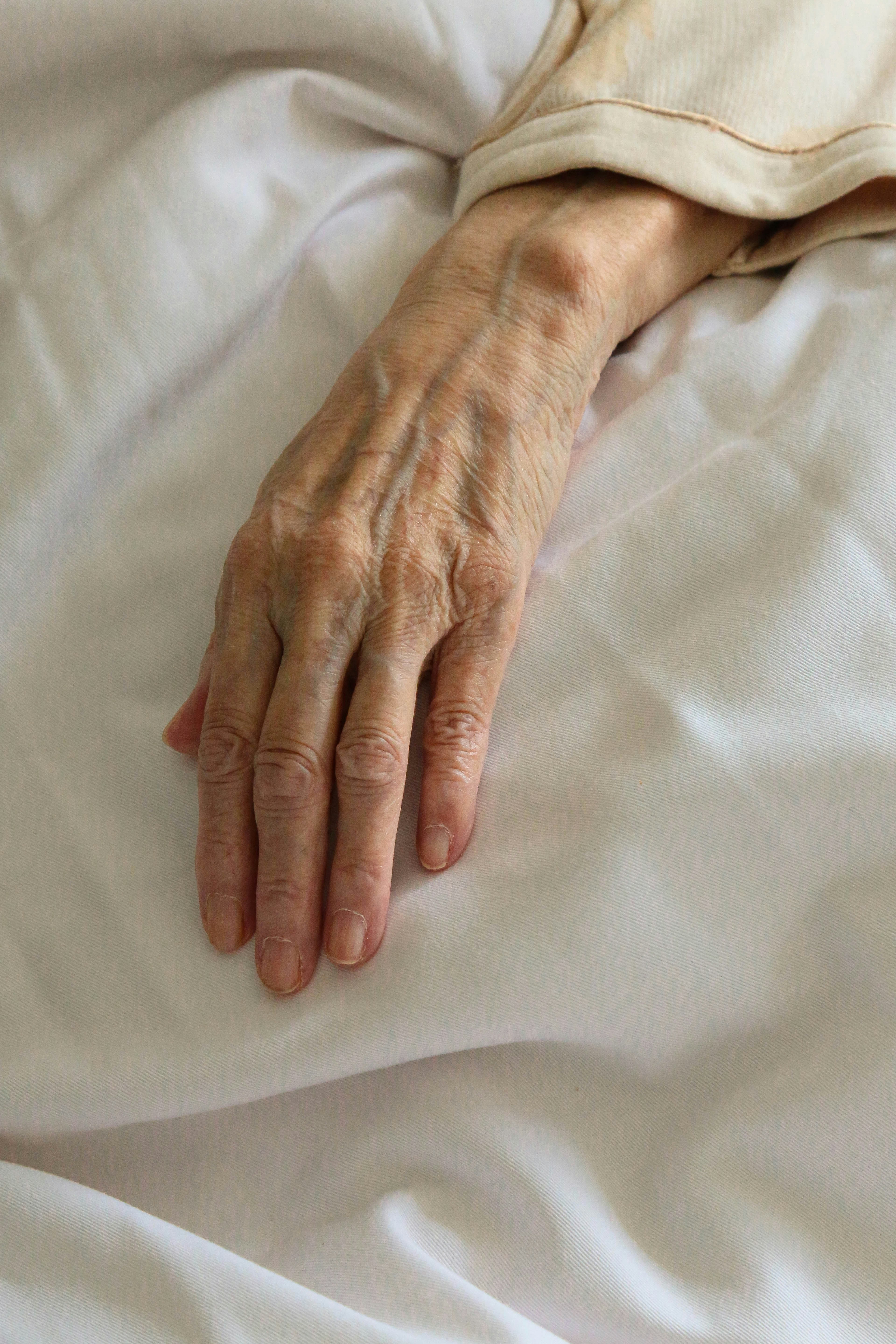 La mano de una mujer enferma sobre una cama | Fuente: Unsplash