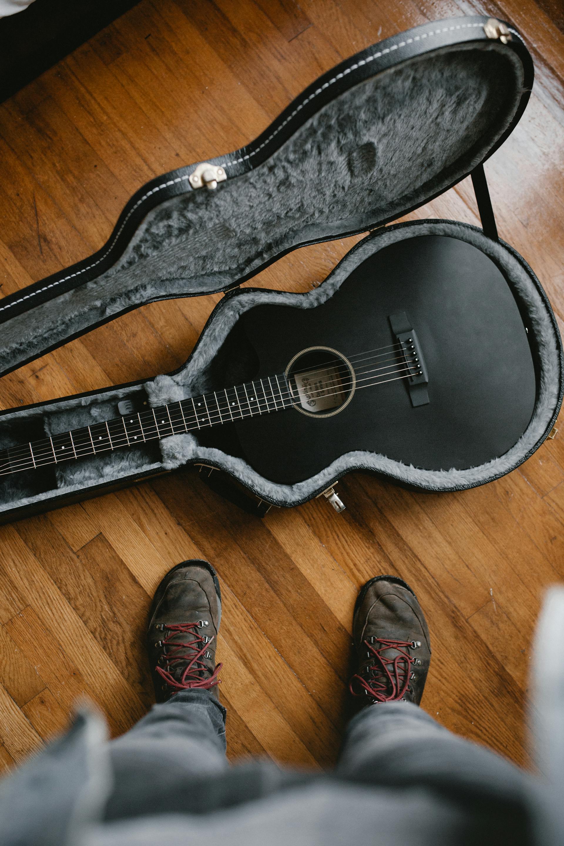 Un hombre de pie cerca de una guitarra | Fuente: Pexels