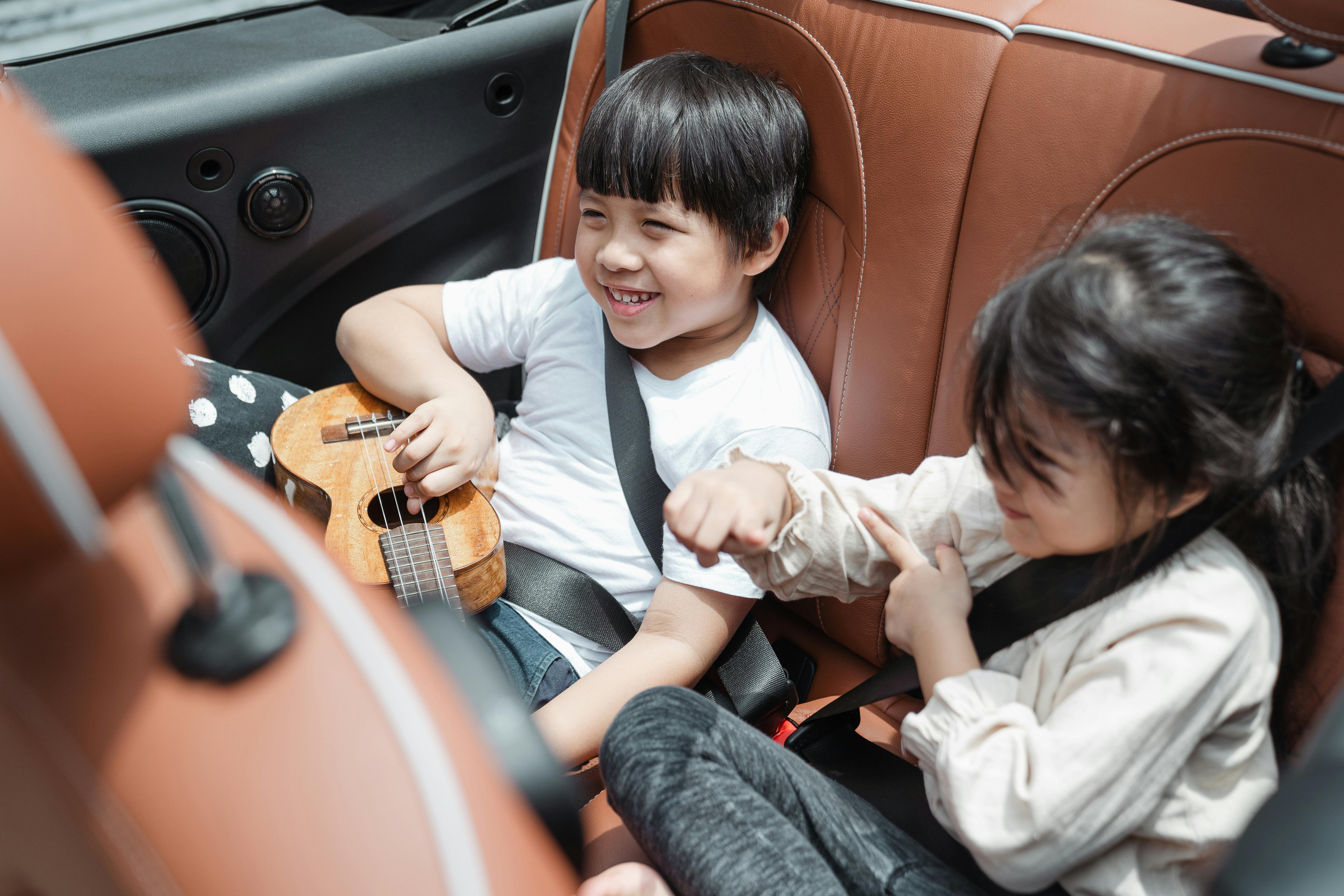 Niños emocionados en el asiento trasero de un auto | Fuente: Pexels