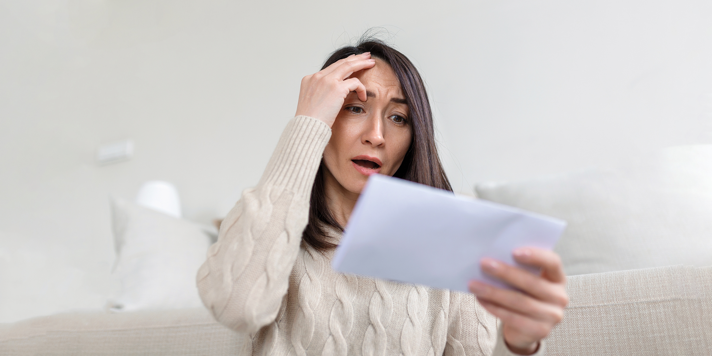 Una mujer mira atónita un sobre | Fuente: Shutterstock