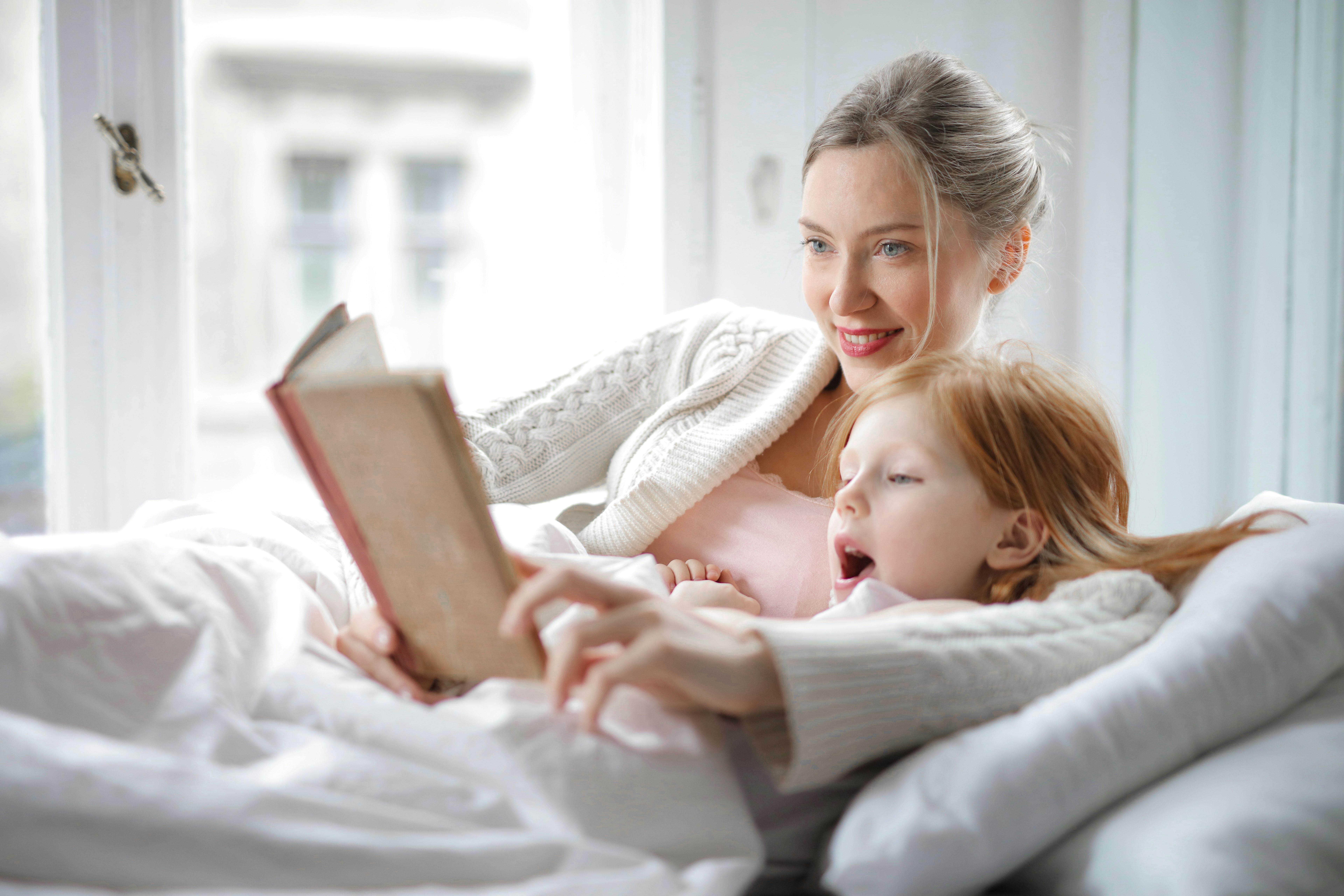 Una madre arropando a su hija en la cama | Fuente: Pexels