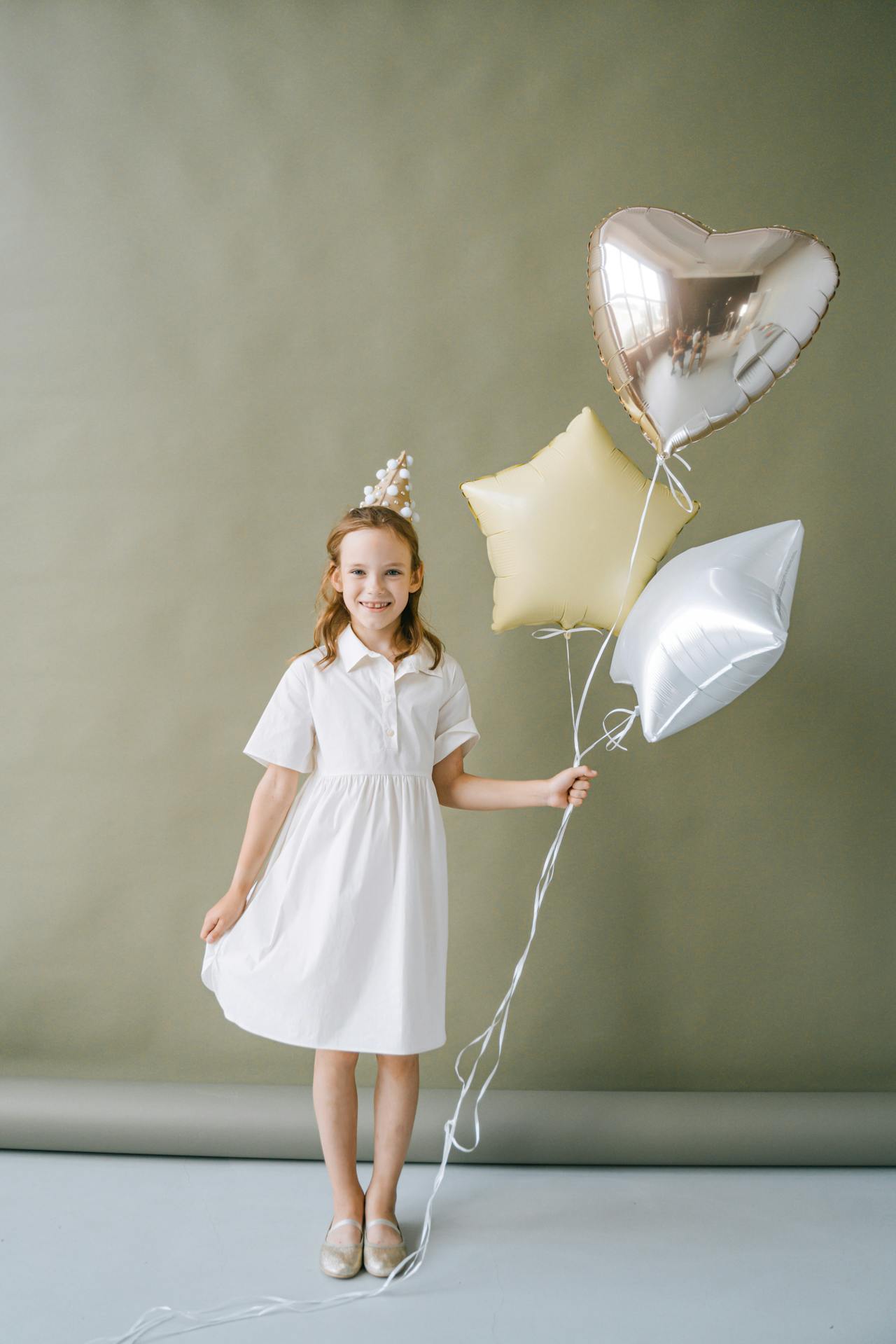Una niña encantada sujetando globos | Fuente: Pexels