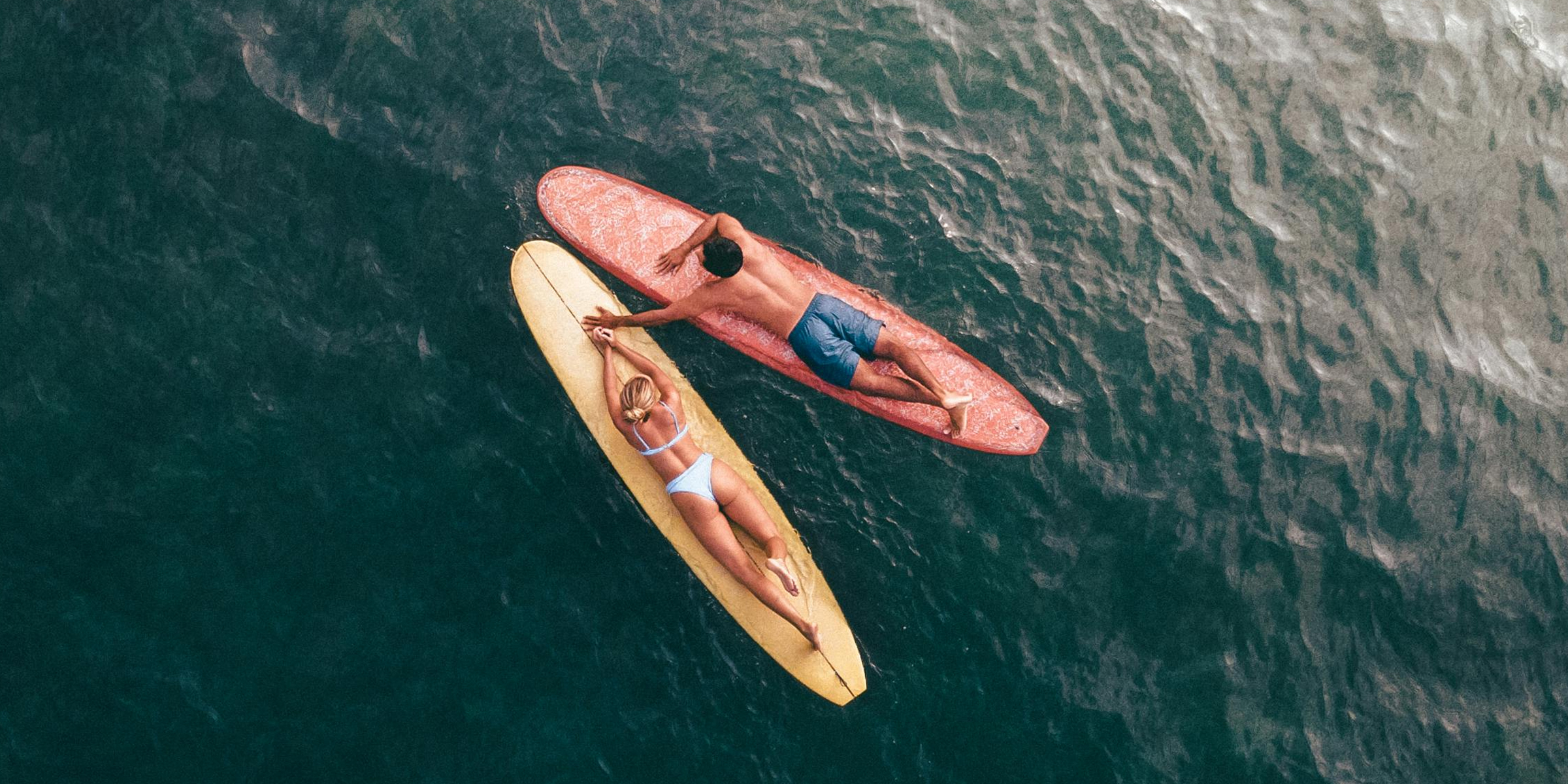 Pareja tumbada sobre tablas de surf. | Fuente: Pexels