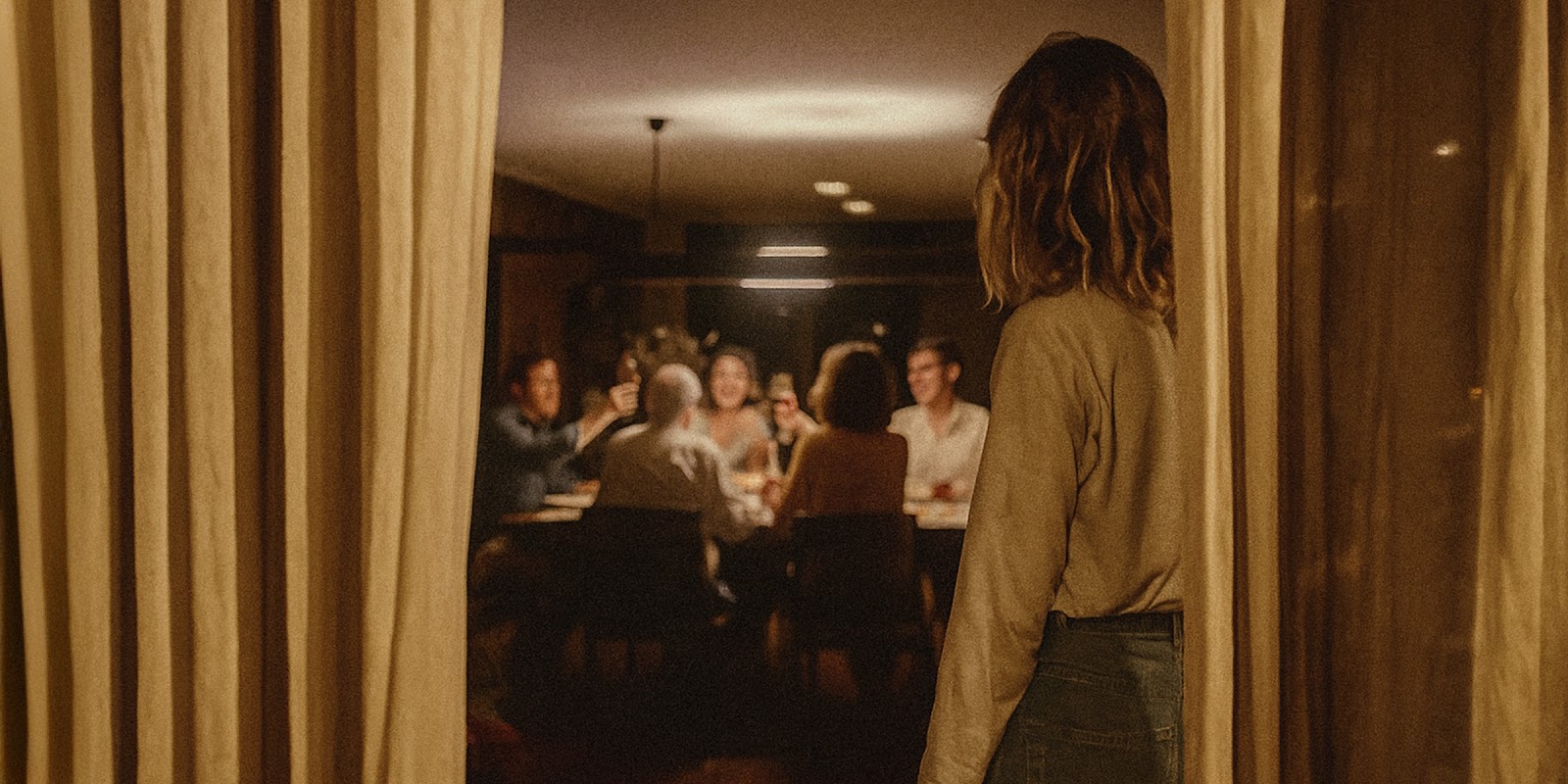Mujer observando una reunión familiar. | Fuente: Sora