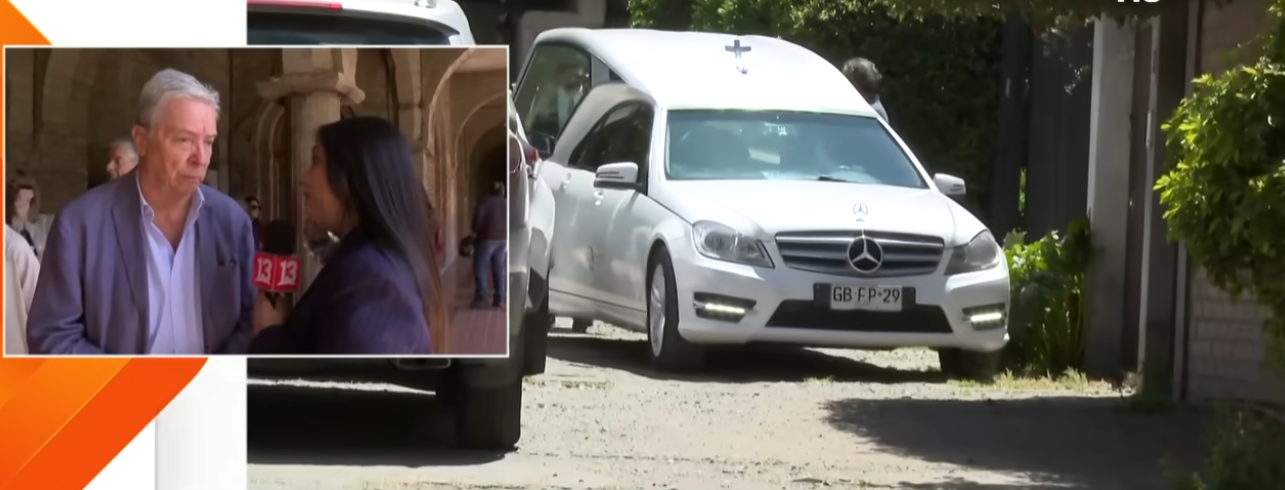 Carlos Ominami siendo entrevistado mientras espera a la salida de la capilla para firmar el libro de condolencias del difunto actor Héctor Noguera | La carroza fúnebre donde transportaban al fallecido actor | Fuente: YouTube/Teletrece