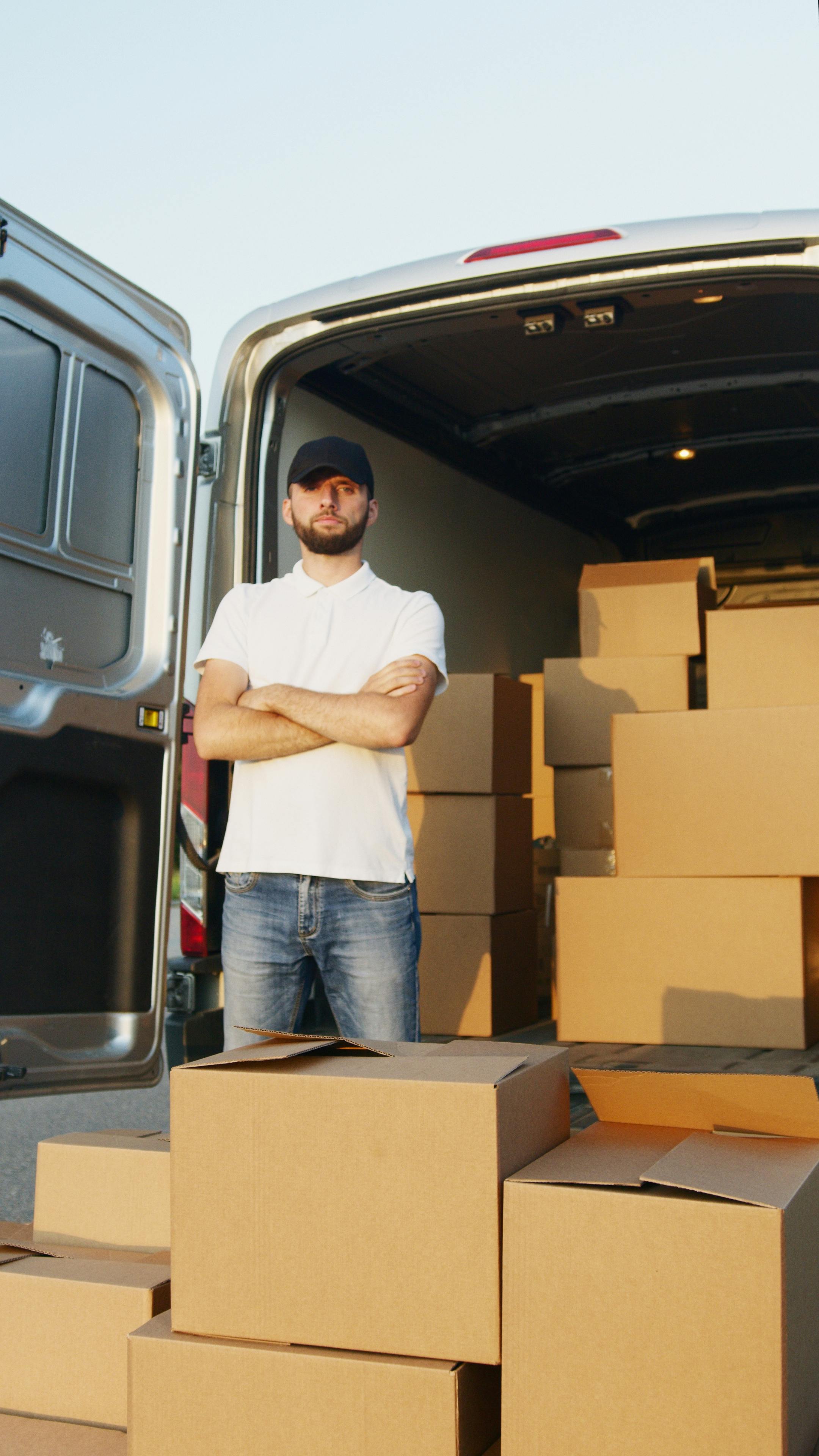 Un hombre fotografiado junto a cajas de cartón | Fuente: Pexels