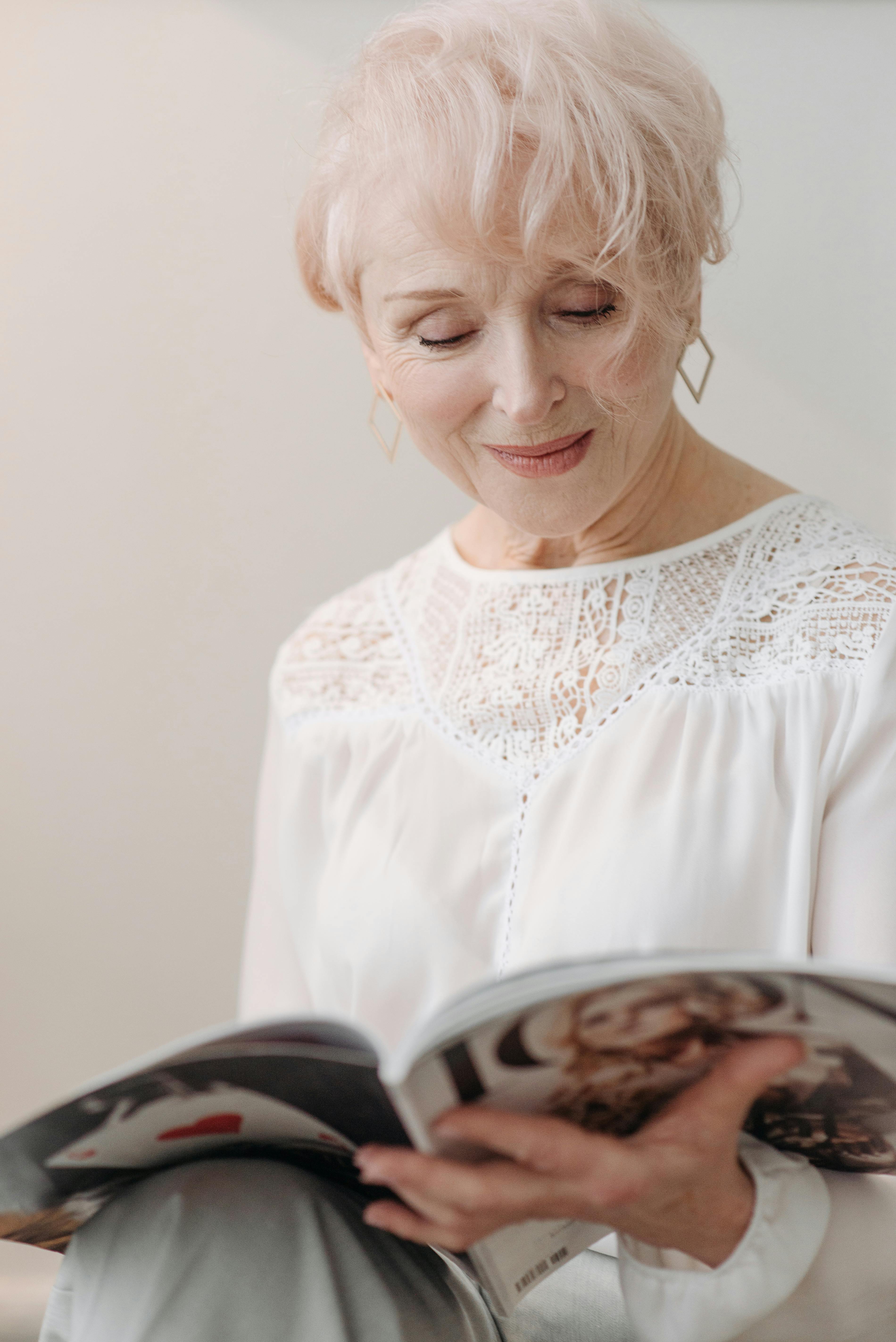 Una mujer mayor sonriente leyendo una revista | Fuente: Pexels
